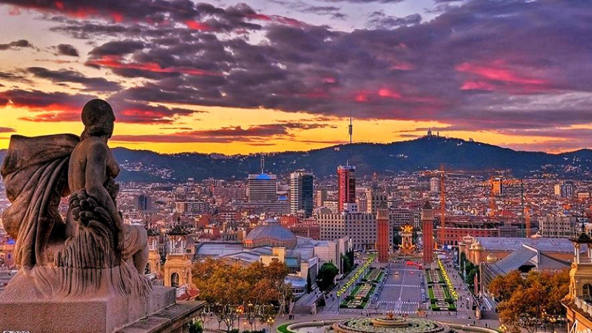 Barcelona cityscape at sunset with statue foreground HD Wallpaper