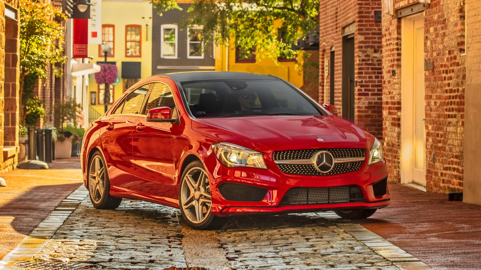 Red Mercedes-Benz CLA Class parked on cobblestone street HD Wallpaper
