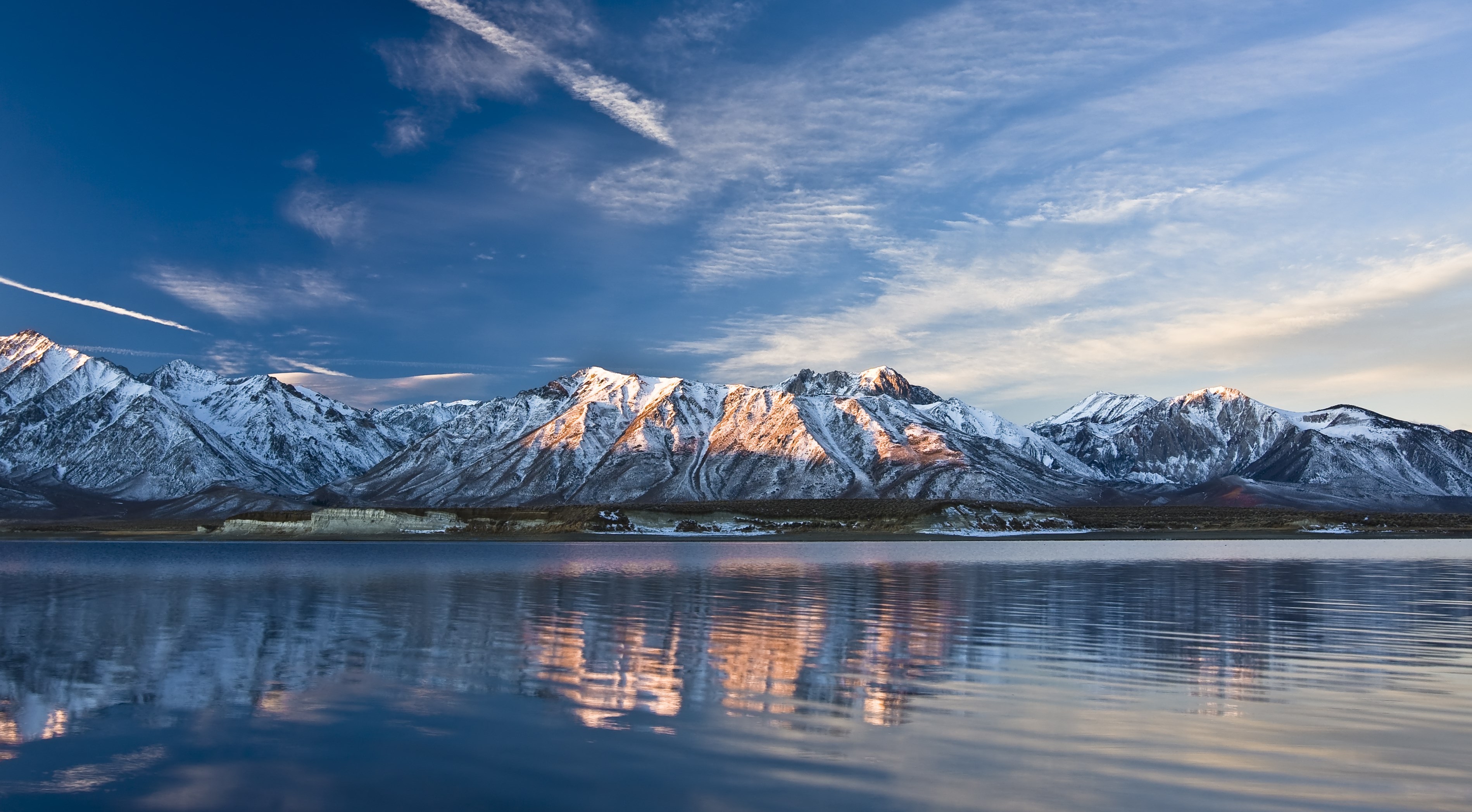 Snow-capped mountains reflected in a lake at sunset HD Wallpaper