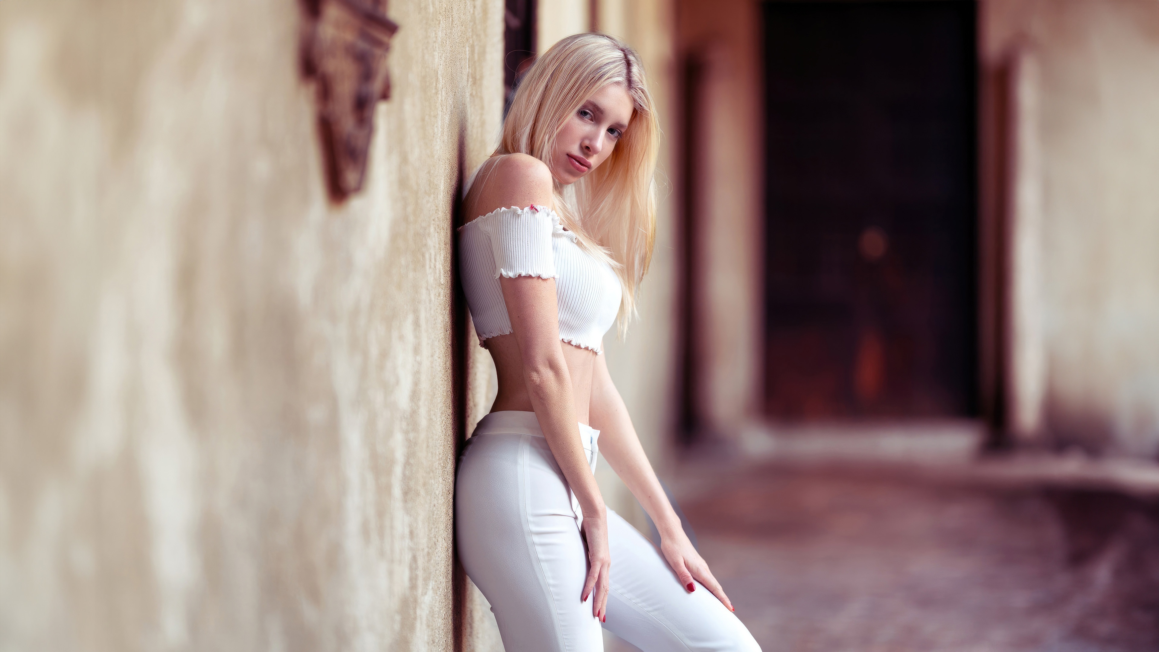 Girl in white clothing leaning against a wall HD Wallpaper