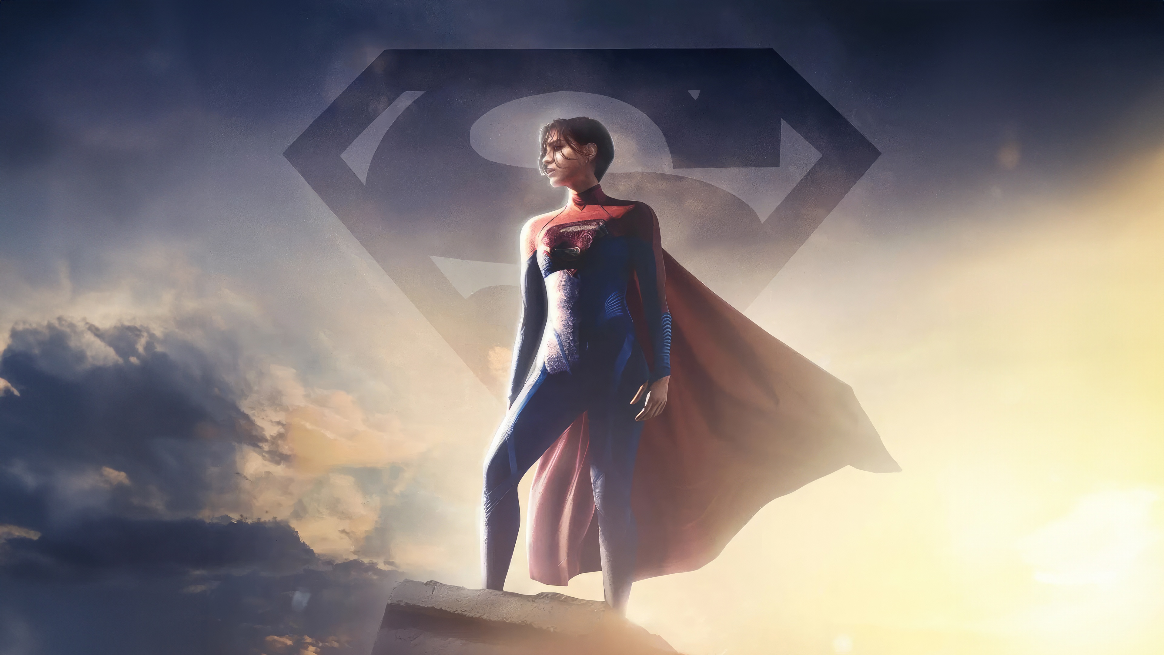 Supergirl stands on a rock with a Superman logo behind her HD Wallpaper