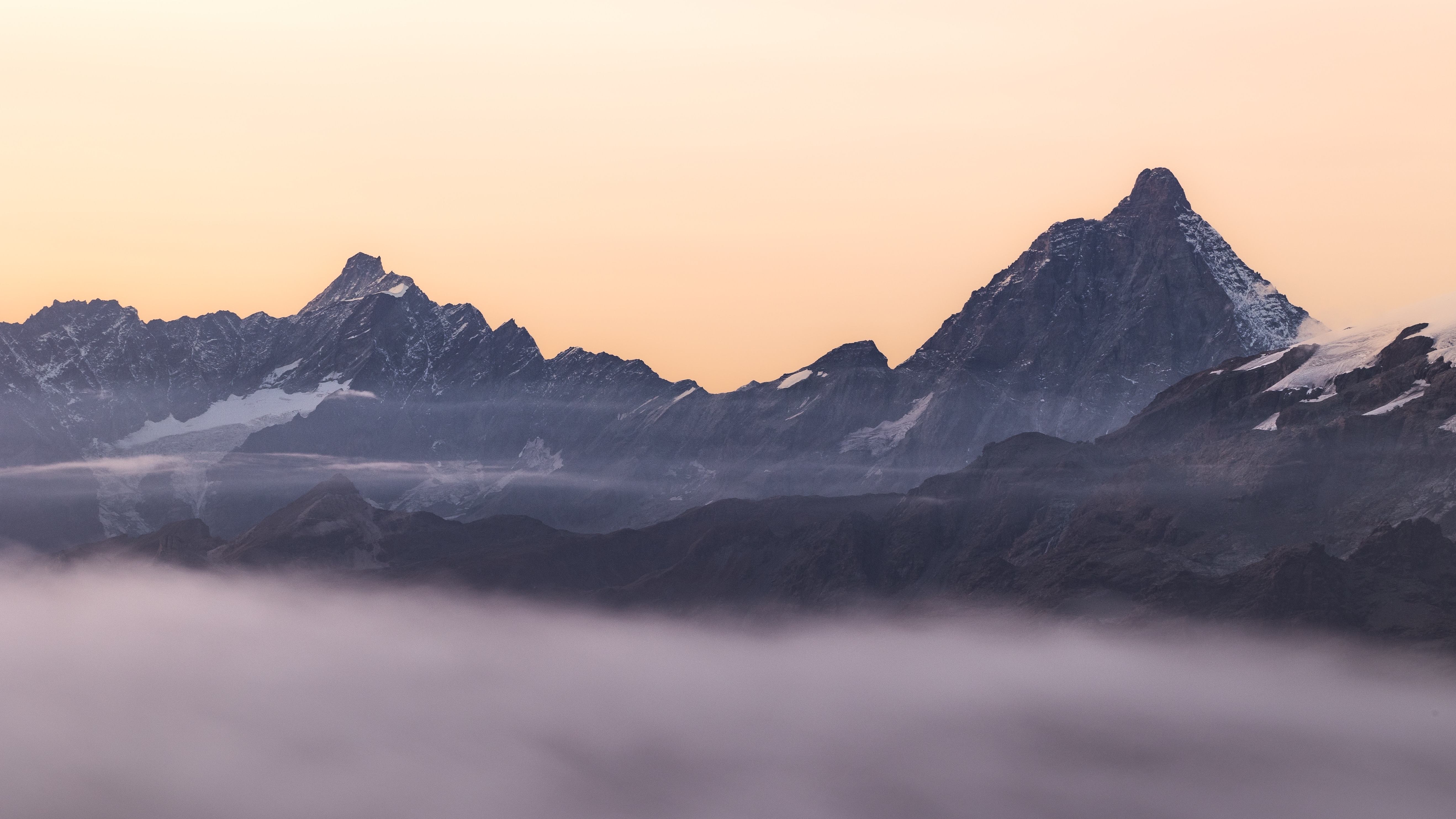 Mountain range shrouded in fog at sunrise HD Wallpaper
