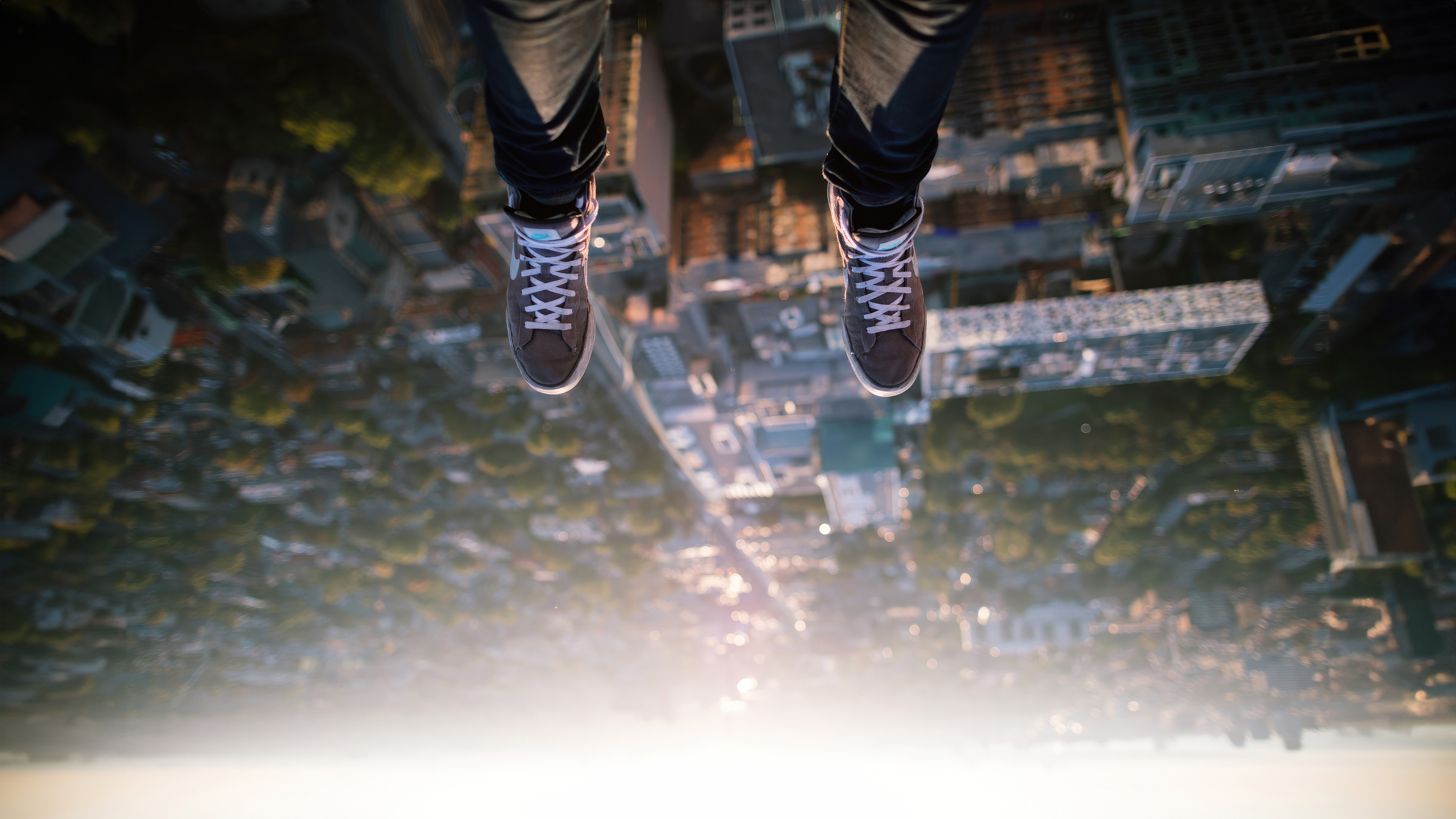 Person's legs hanging over a city HD Wallpaper