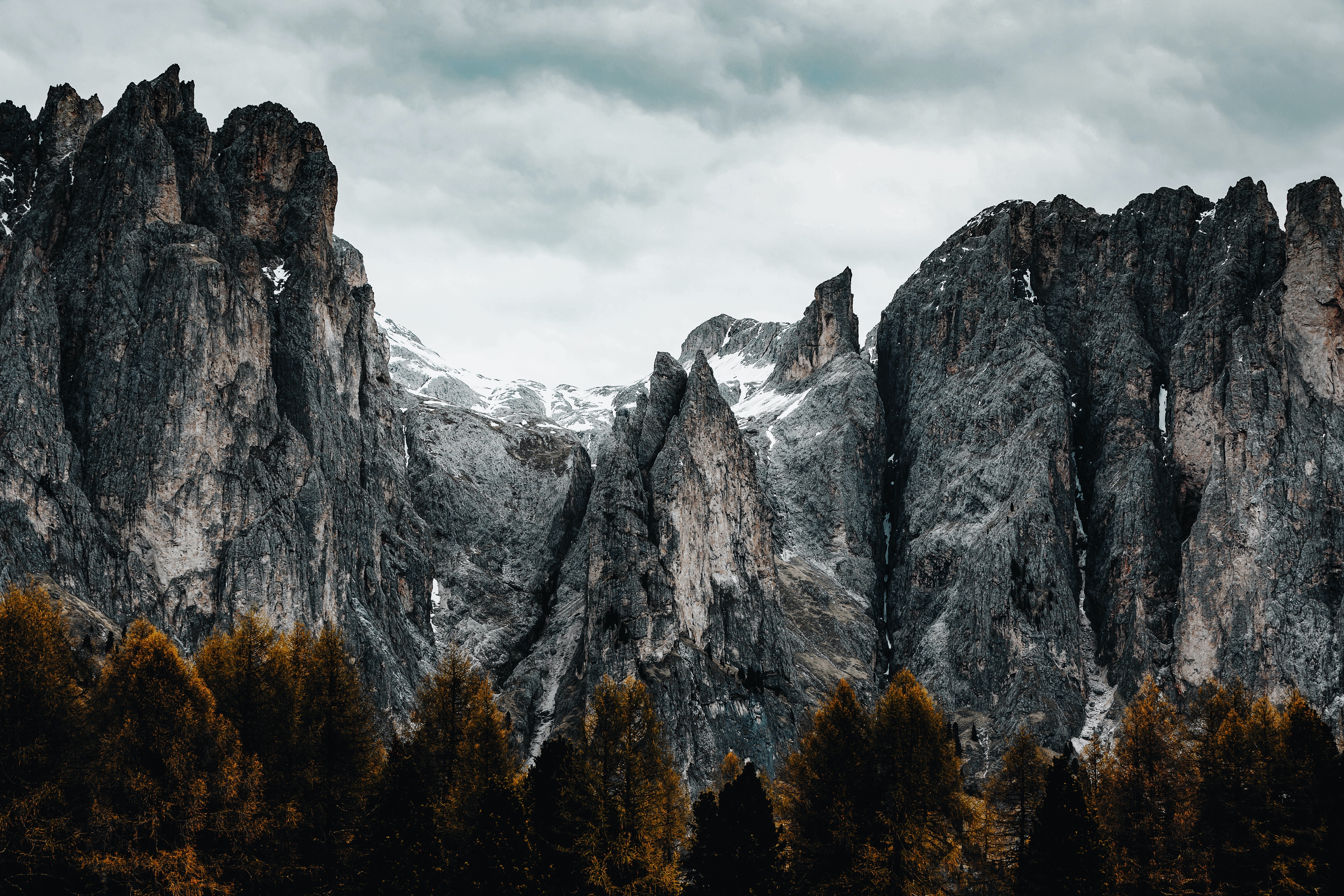 Jagged mountain peaks above a dark forest HD Wallpaper