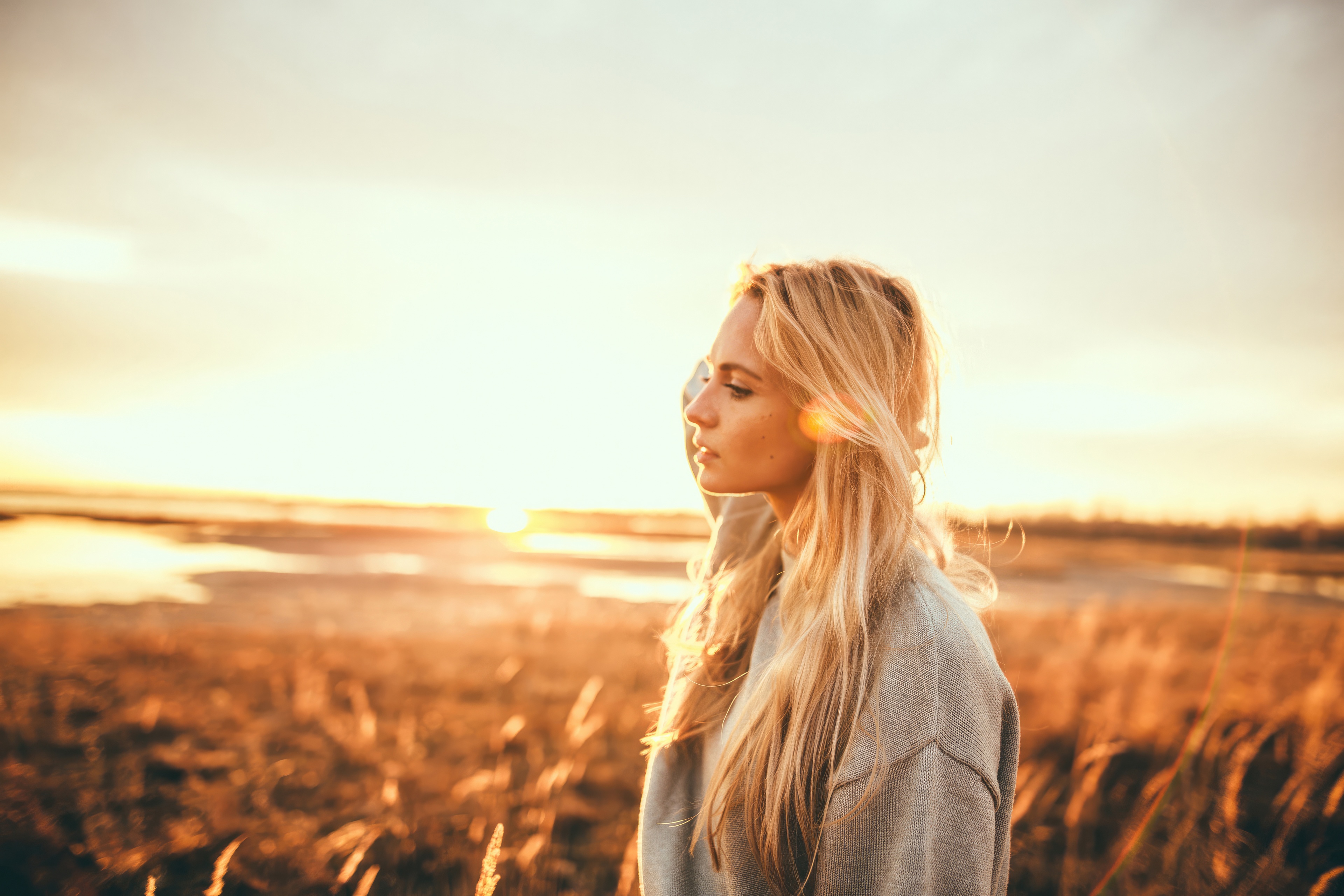 Blonde girl in a sunlit field at sunset HD Wallpaper