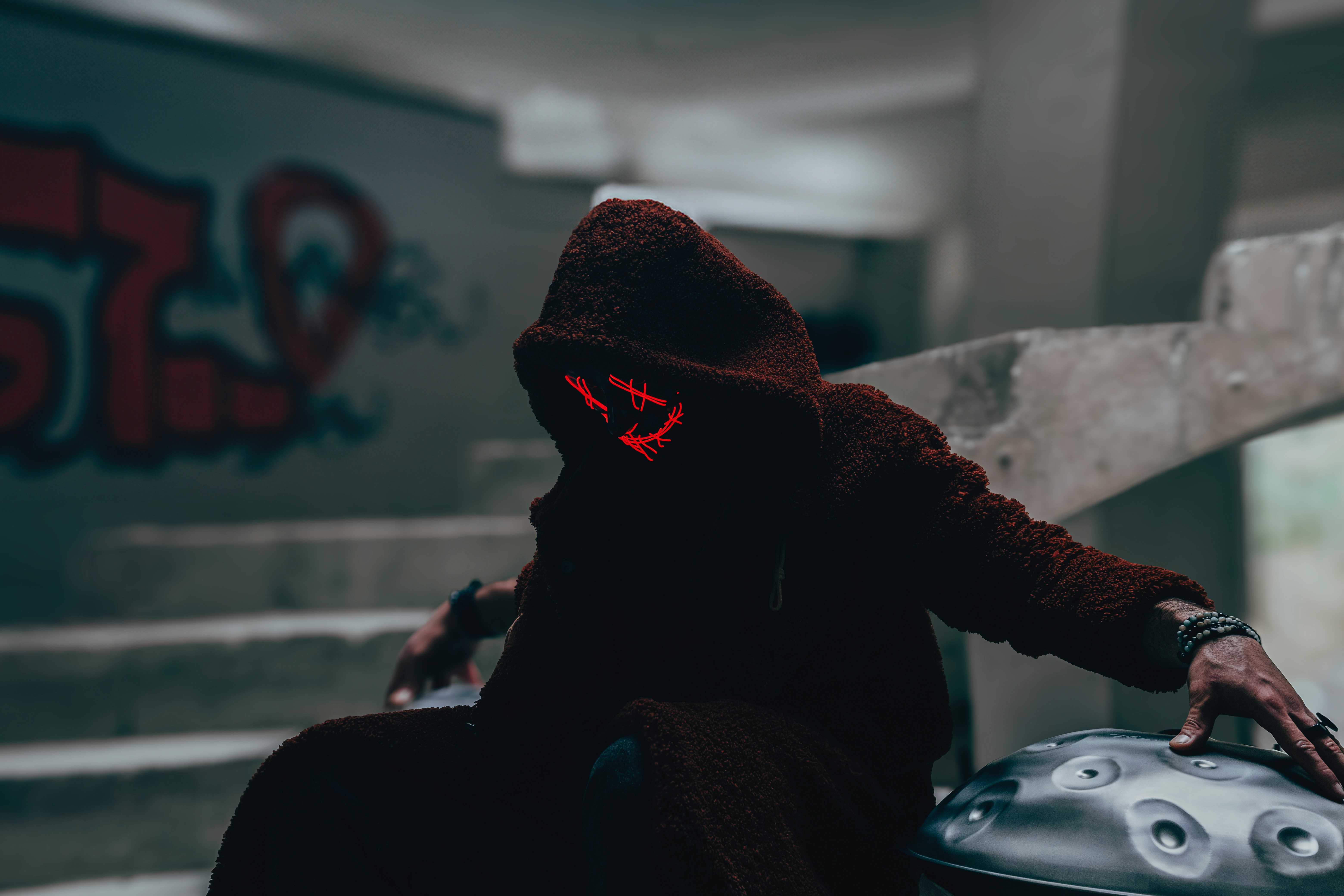 Person in a hooded robe with a glowing mask and a handpan HD Wallpaper