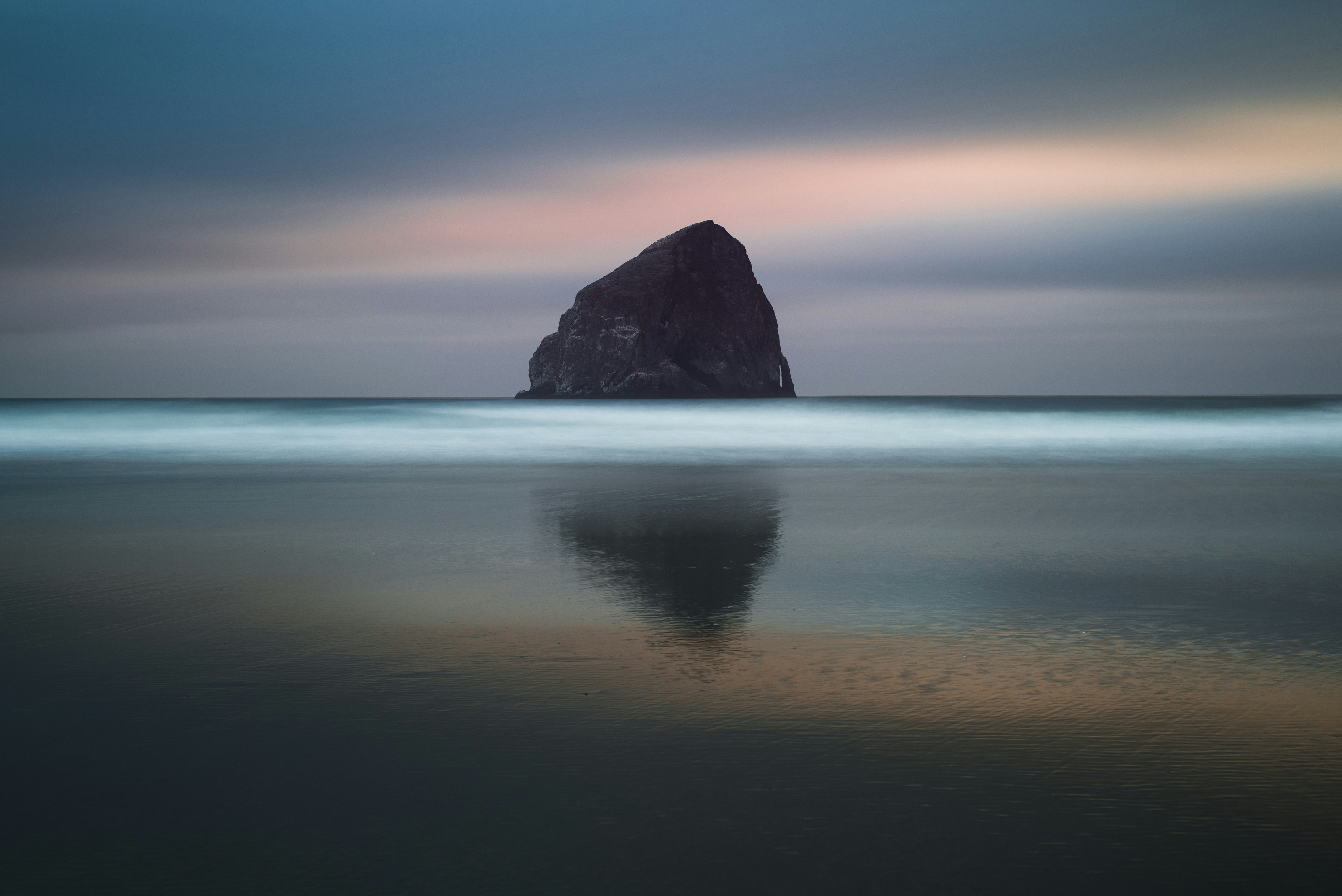 Large rock formation in the ocean at dusk HD Wallpaper