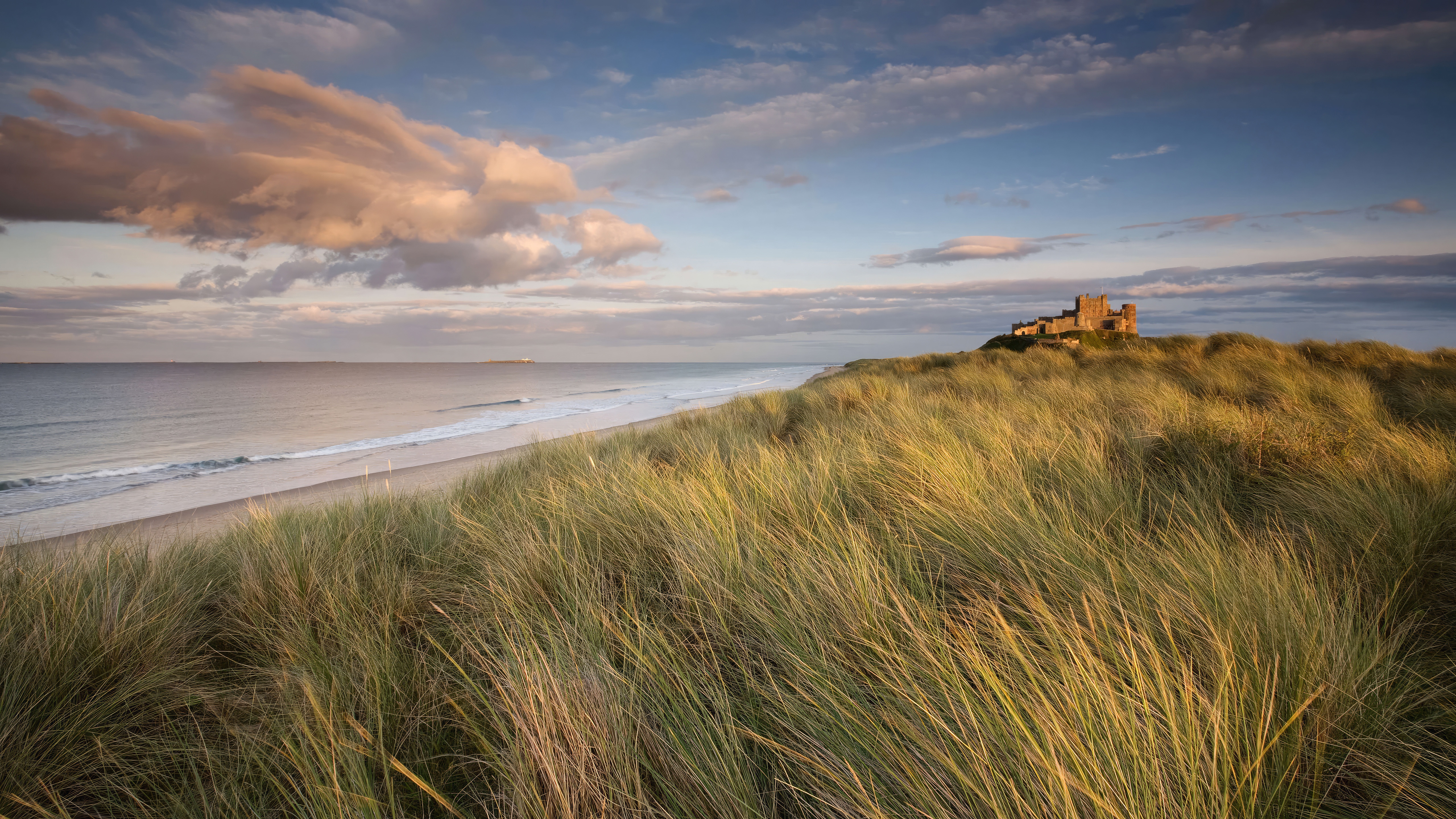 Bamburgh Castle on a grassy dune overlooking the sea HD Wallpaper