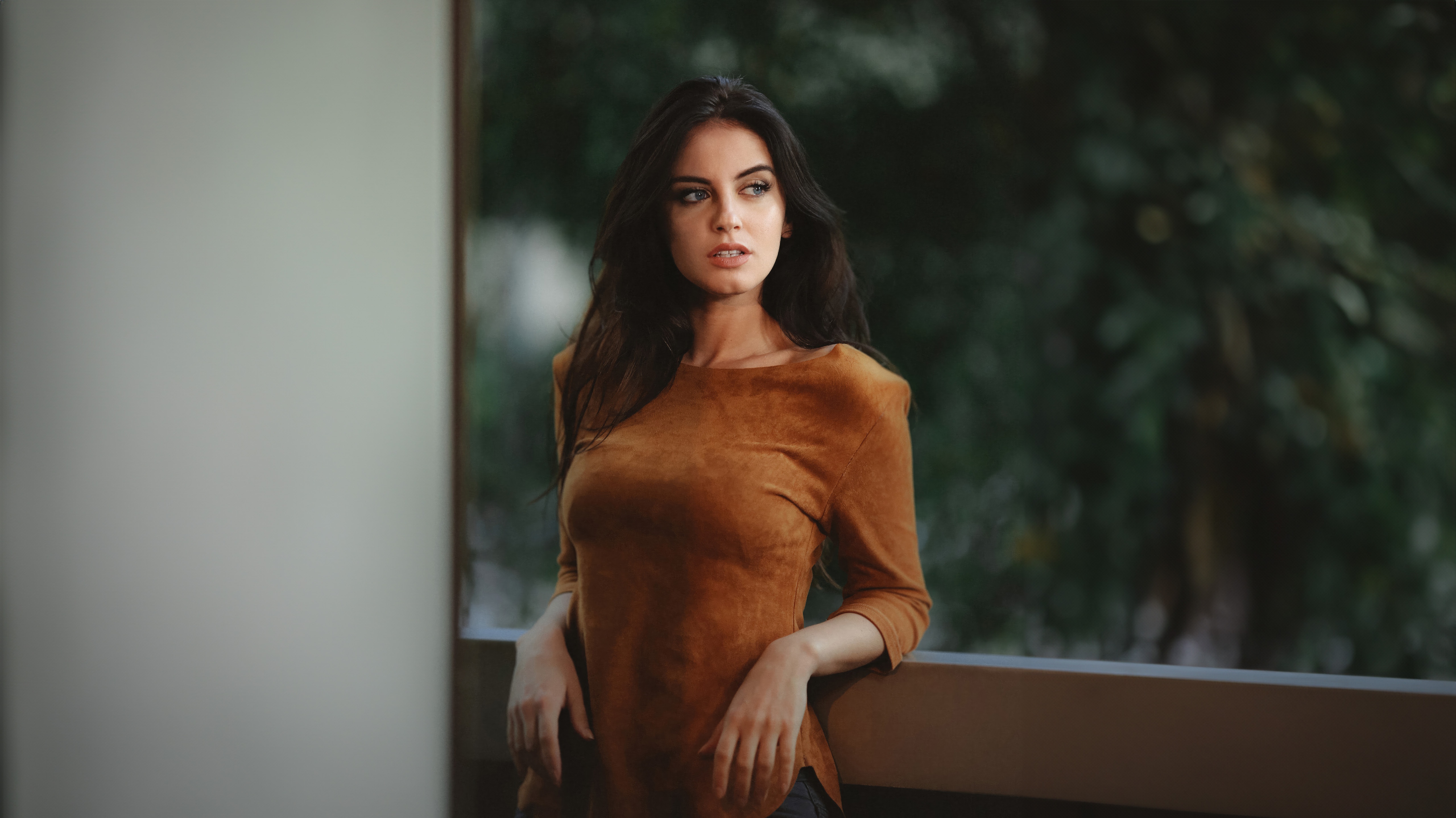Woman in a brown suede top standing on a balcony HD Wallpaper