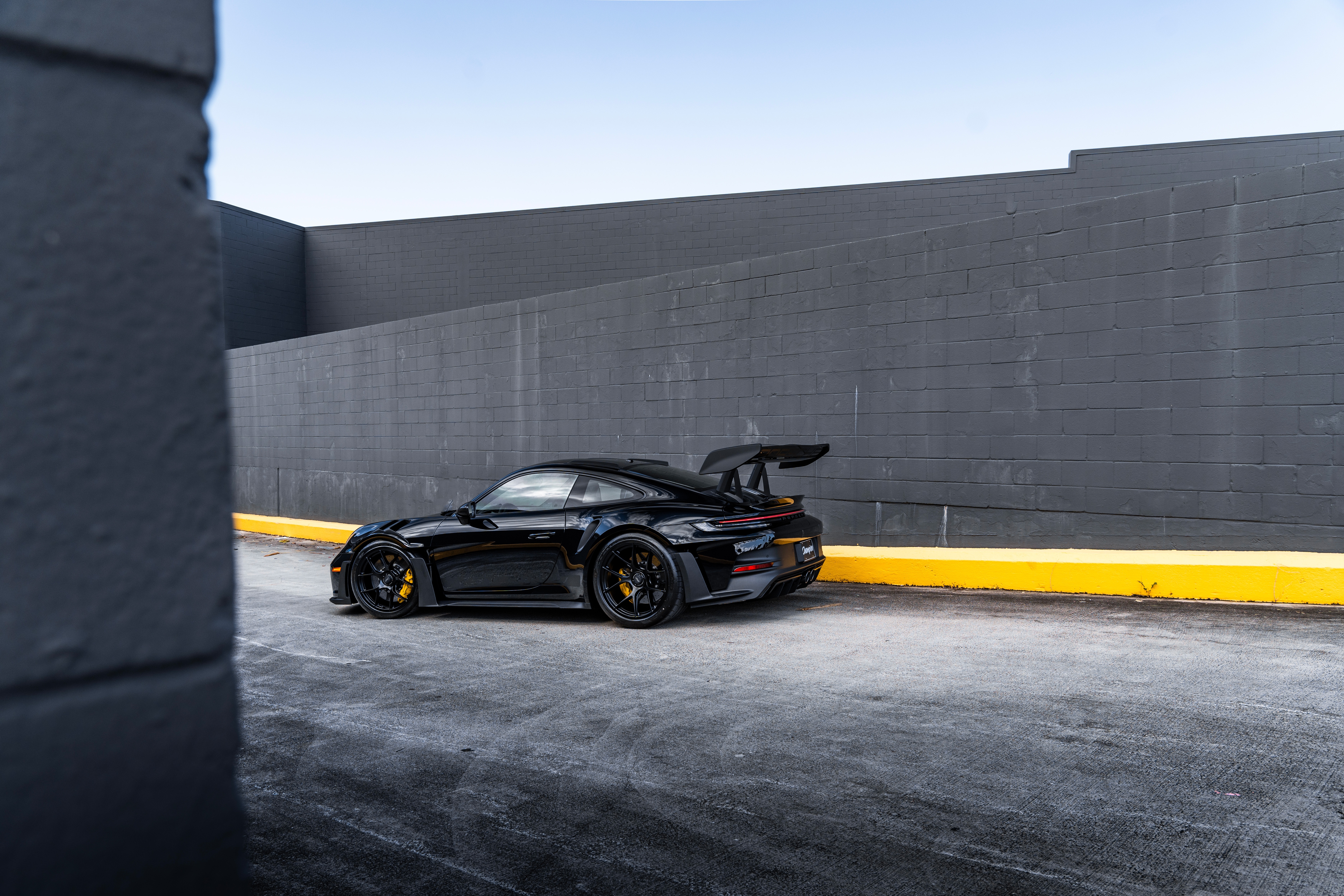 Black Porsche 992 GT3 RS parked by a wall HD Wallpaper