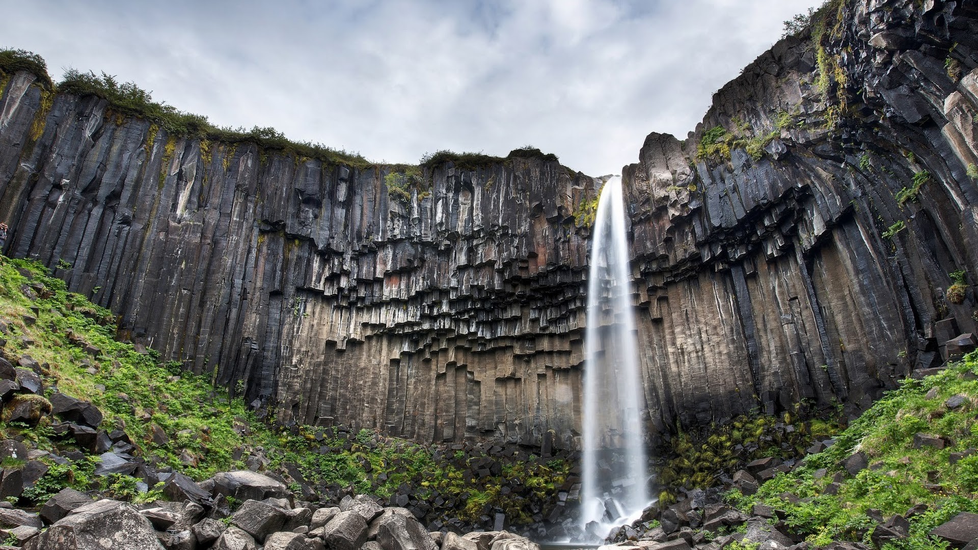 Waterfall cascading over basalt columns in Iceland HD Wallpaper