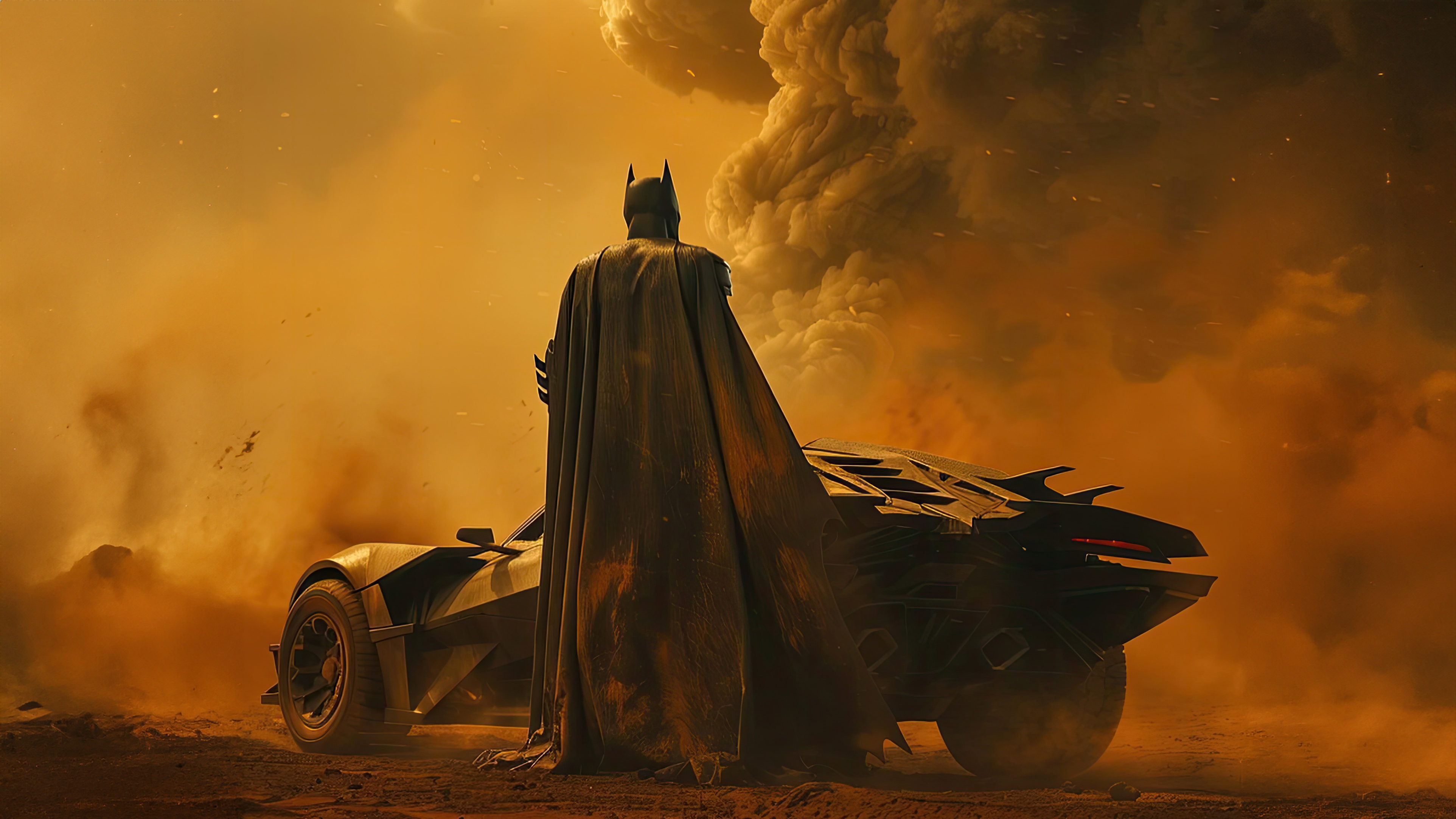 Batman standing next to the Batmobile in a dusty environment HD Wallpaper