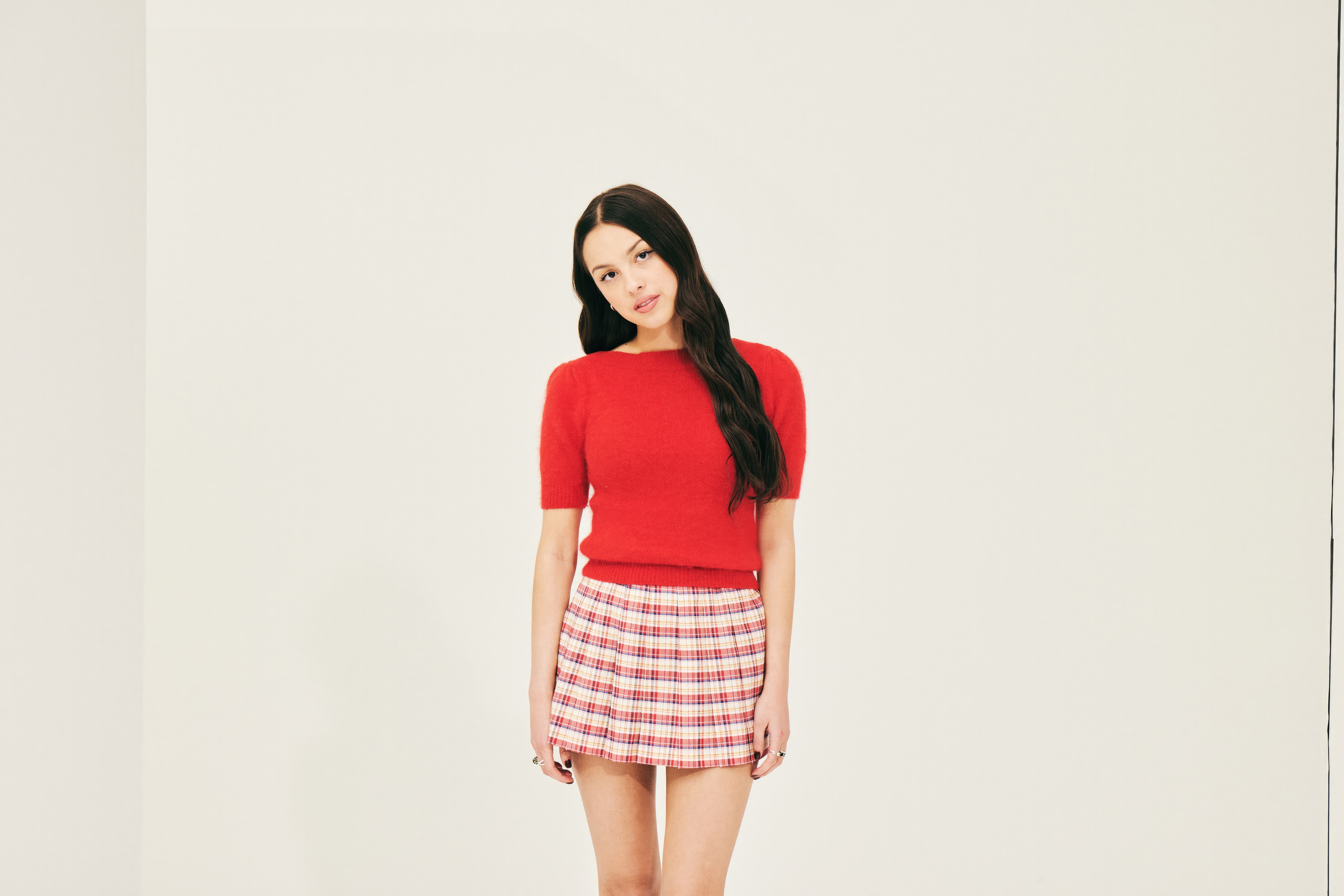 Olivia Rodrigo in a red top and plaid skirt HD Wallpaper