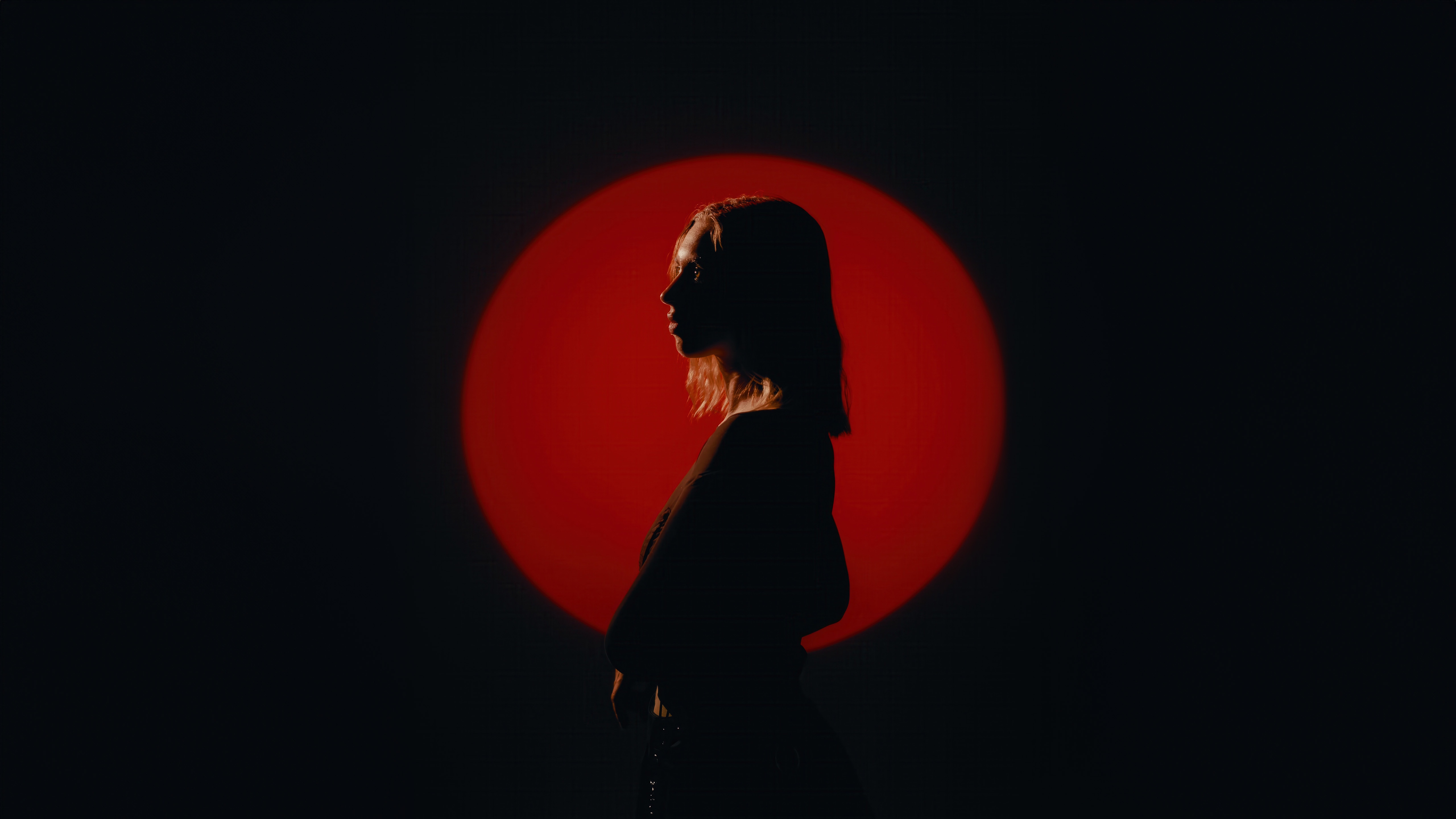 Girl silhouetted against a red circle in a dark room HD Wallpaper