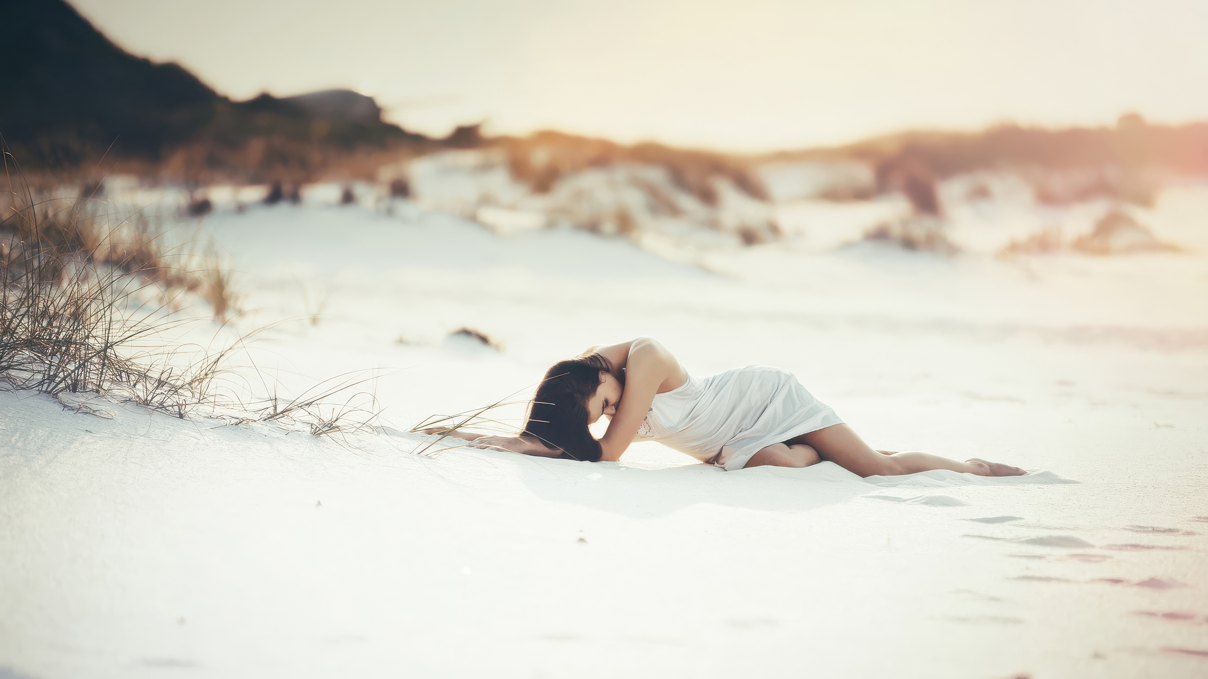 Woman in white dress lying on a sandy beach HD Wallpaper