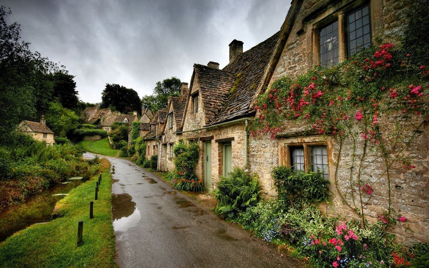 Stone cottages with climbing roses along a wet street in England HD Wallpaper