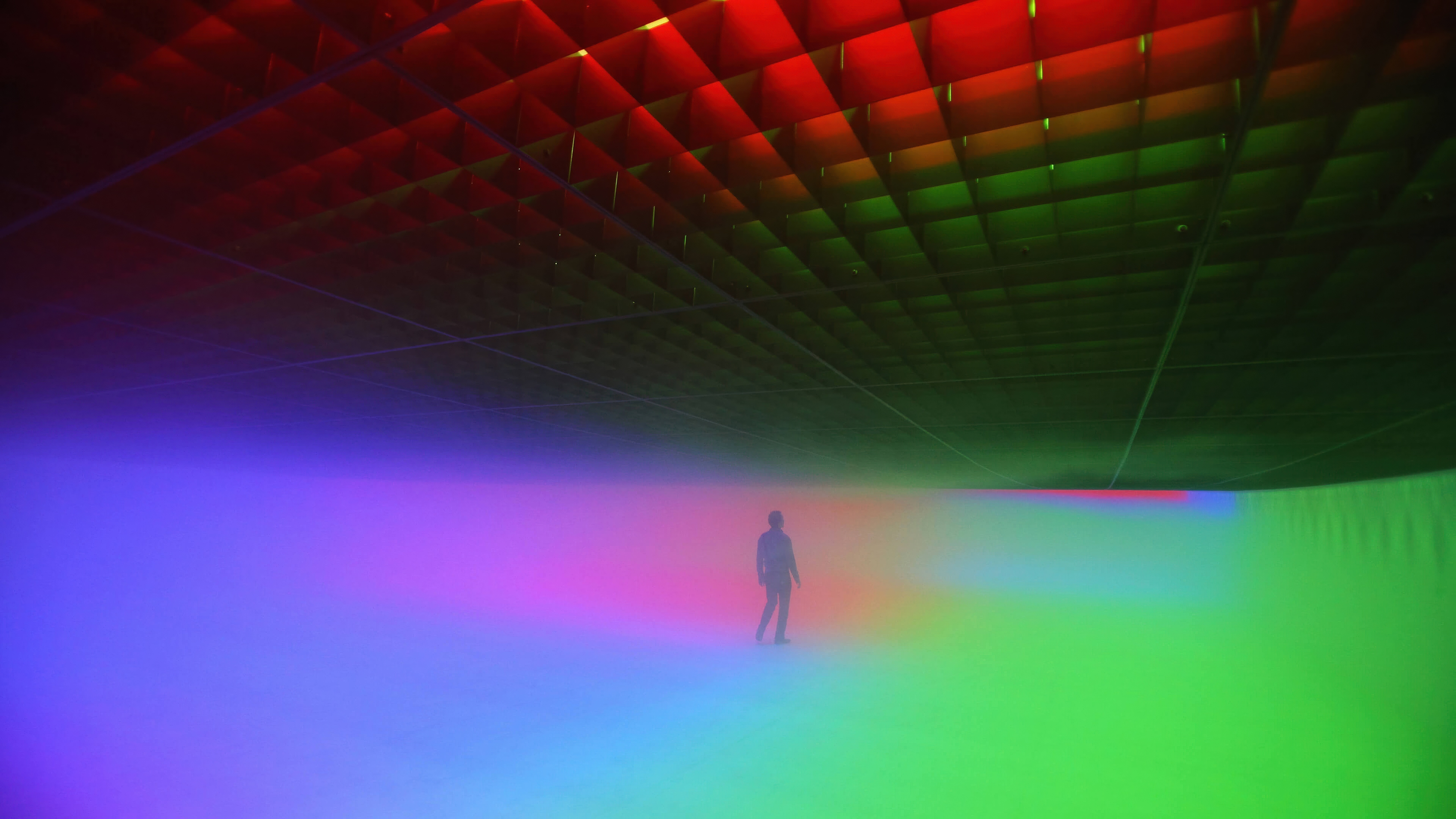 Person standing in a colorful light installation HD Wallpaper