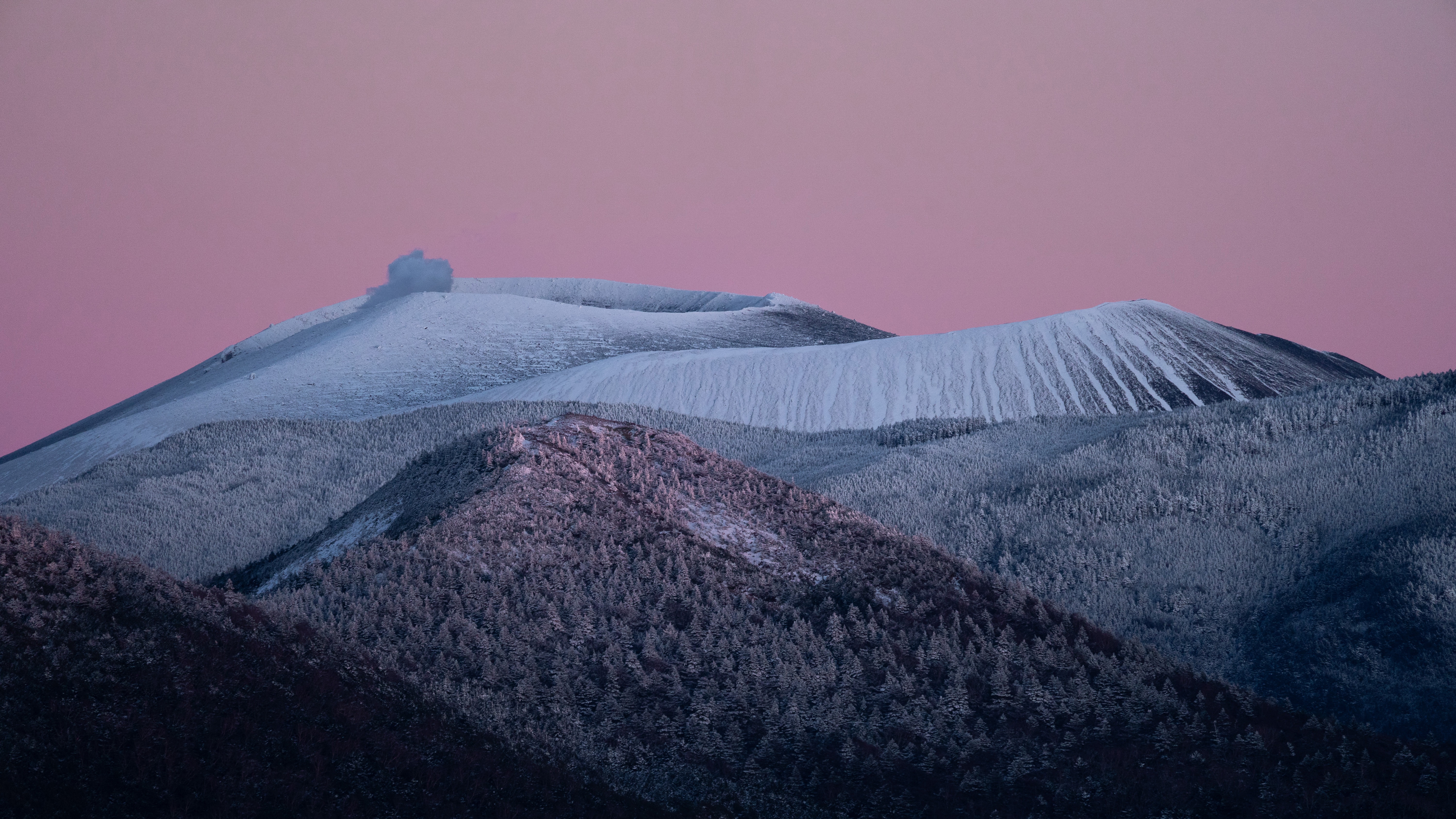 Snow-covered volcano erupting under a pink sky HD Wallpaper