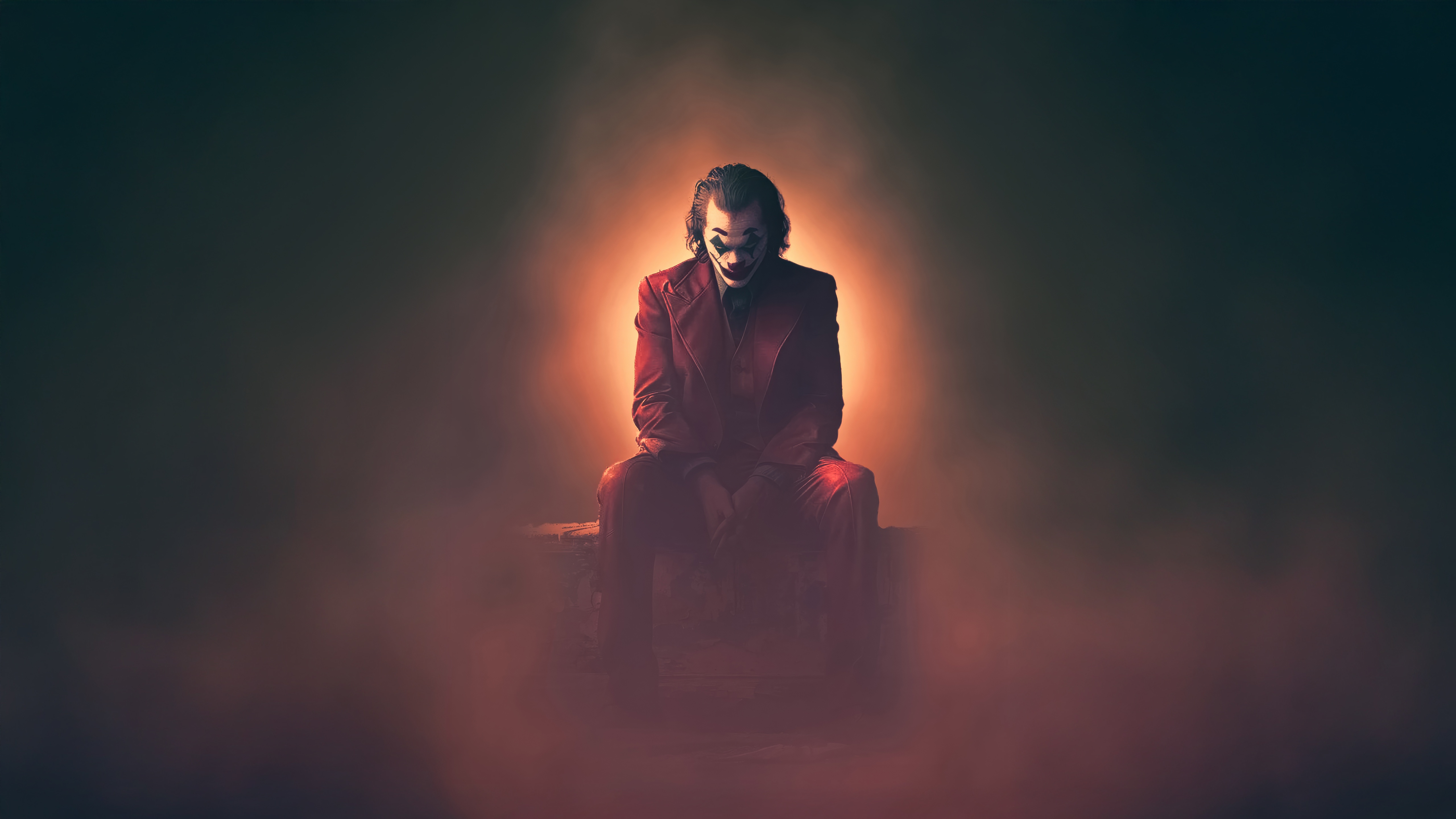 Joker sitting in red suit with orange glow HD Wallpaper