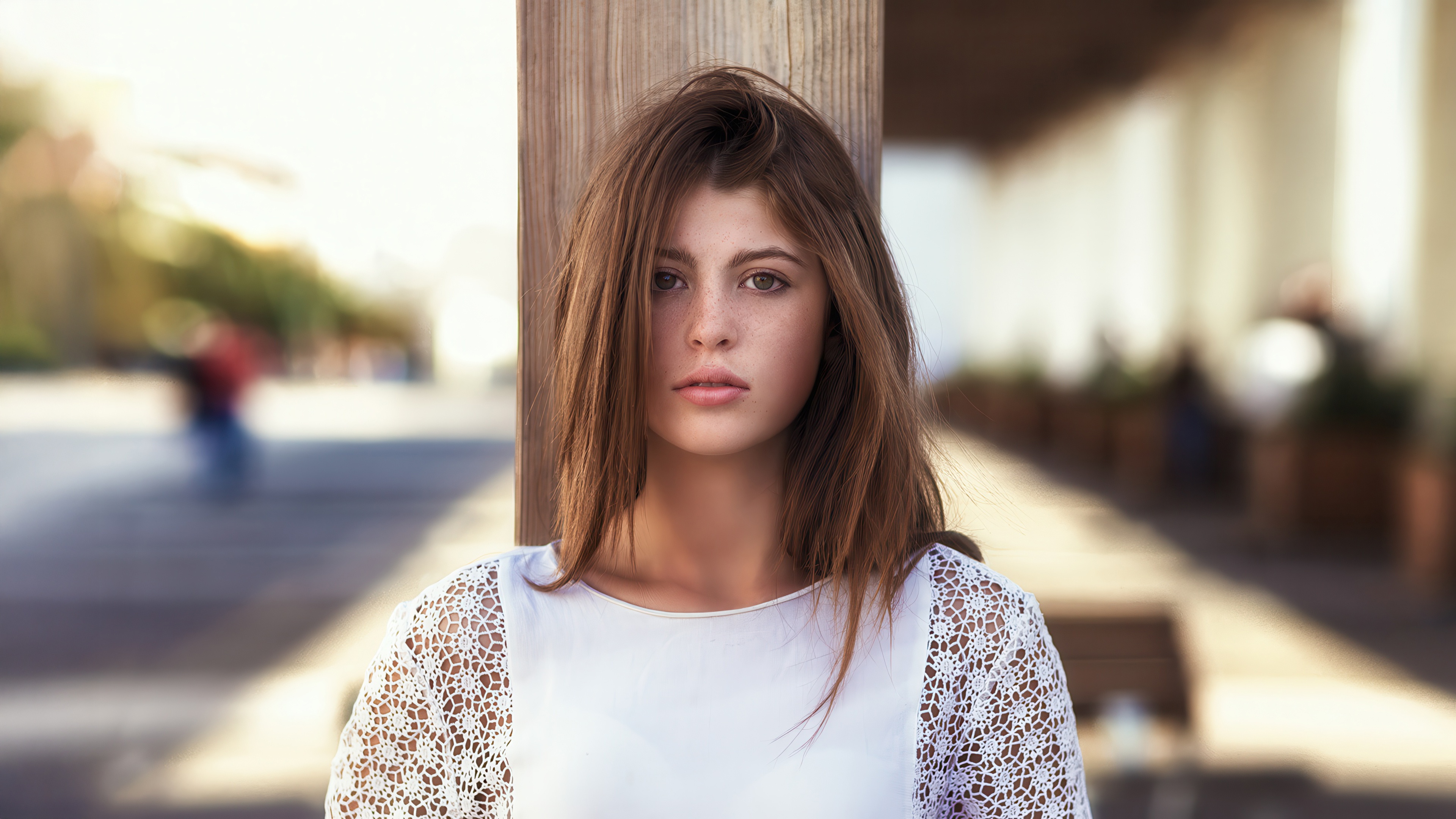 Young woman with brown hair leaning on a wooden post HD Wallpaper