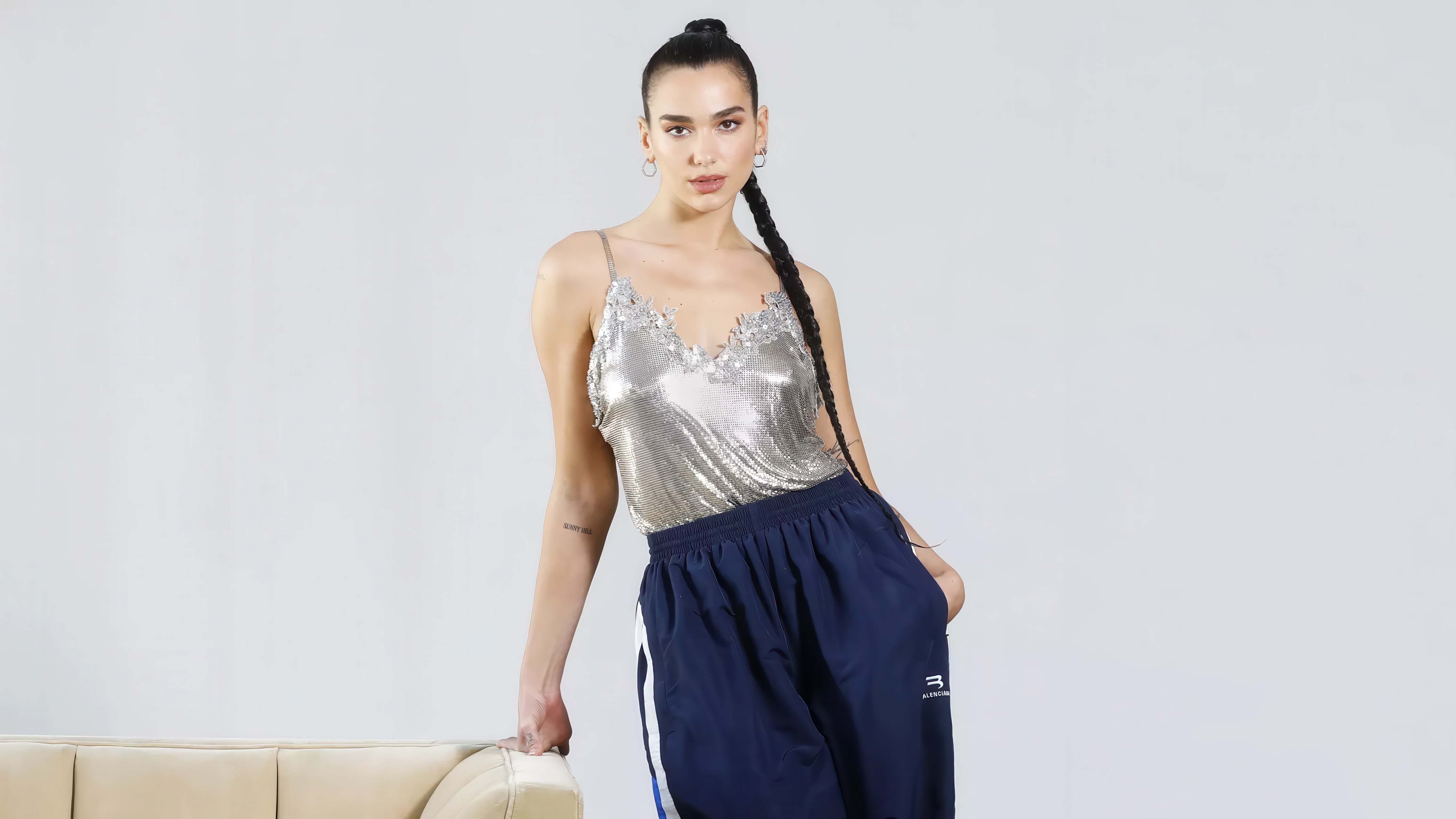 Dua Lipa in a silver top and blue track pants HD Wallpaper
