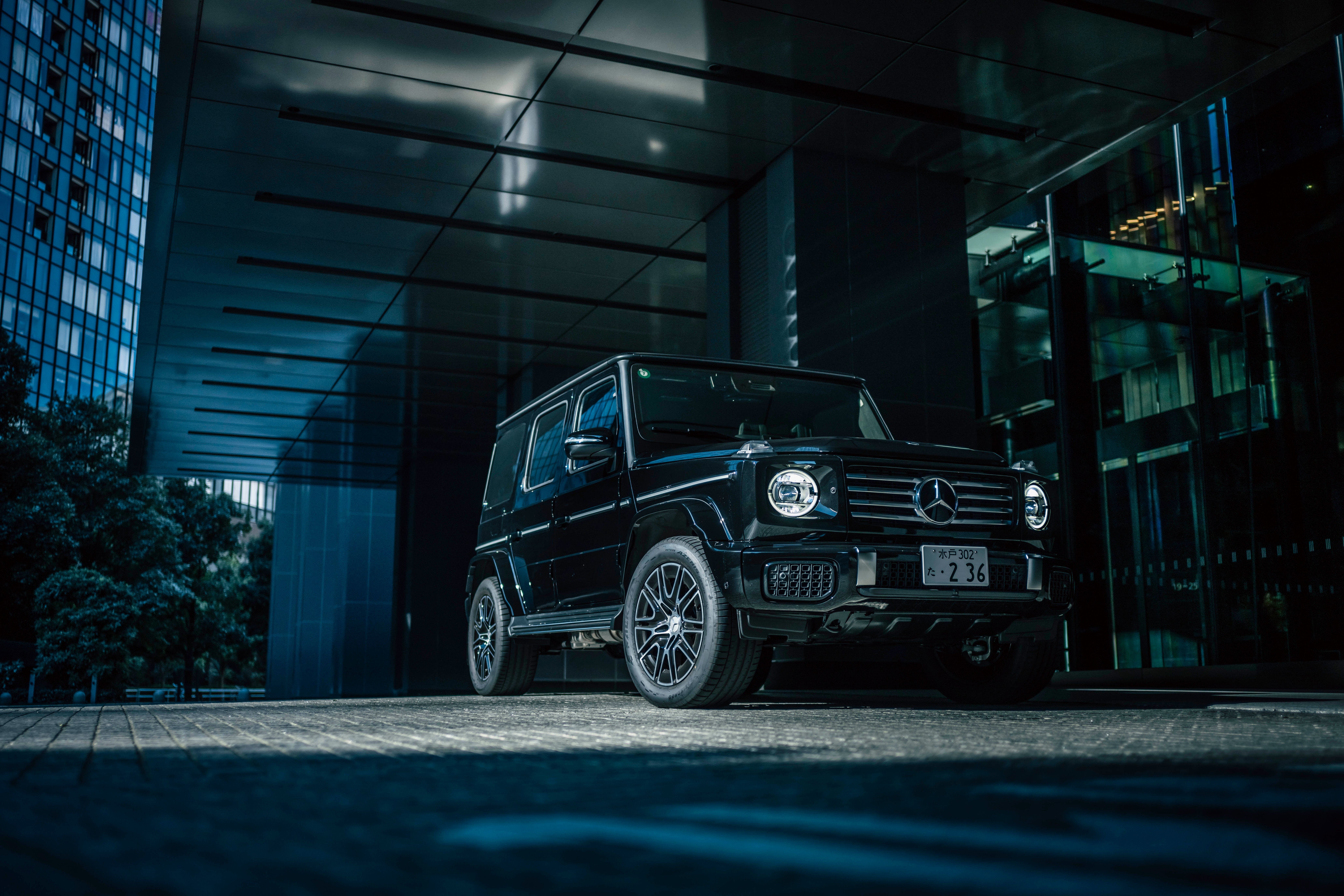 Black Mercedes Benz G 450d parked in front of a modern building HD Wallpaper