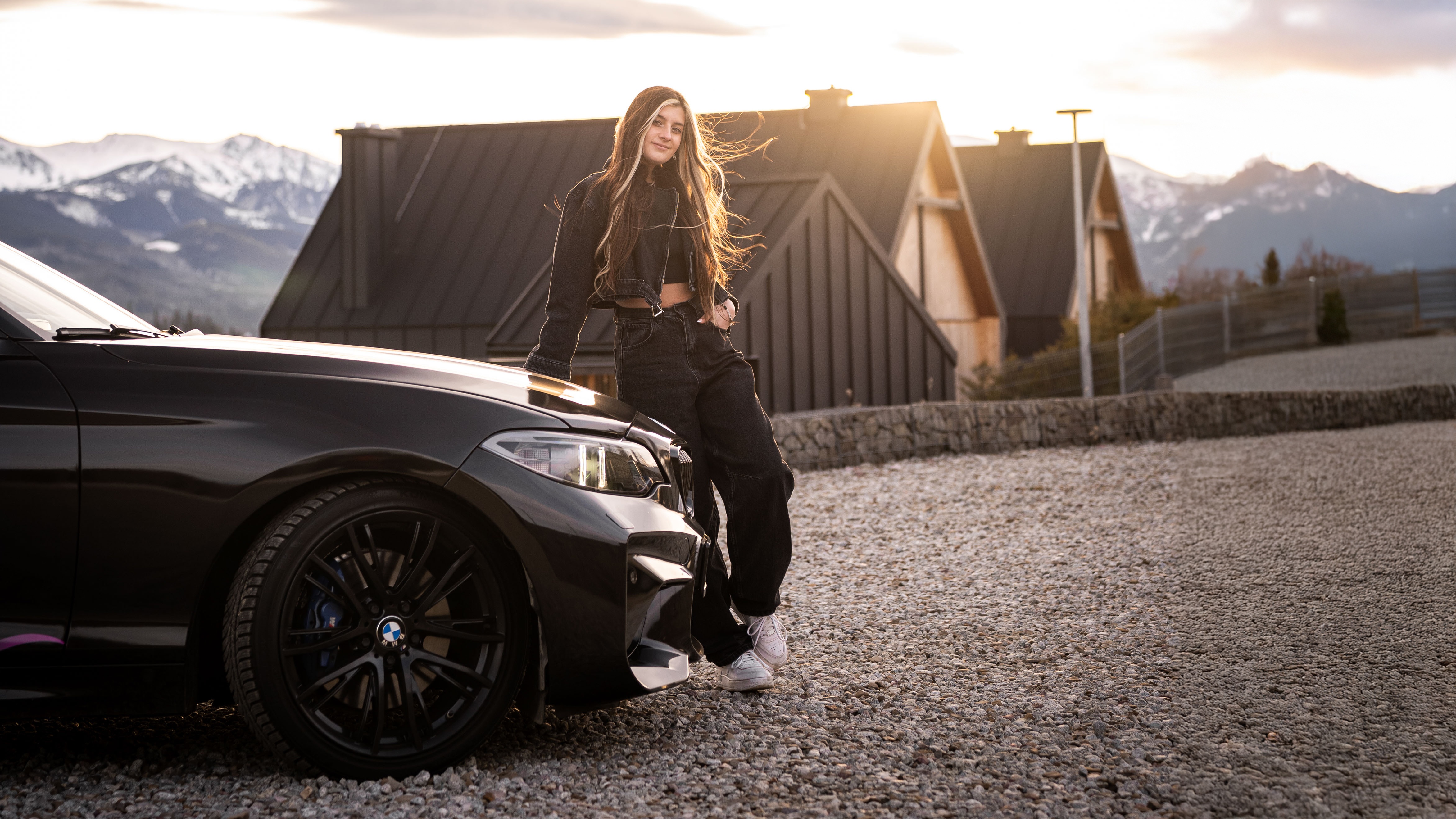 Girl leaning on a black BMW M car with mountains in the background HD Wallpaper