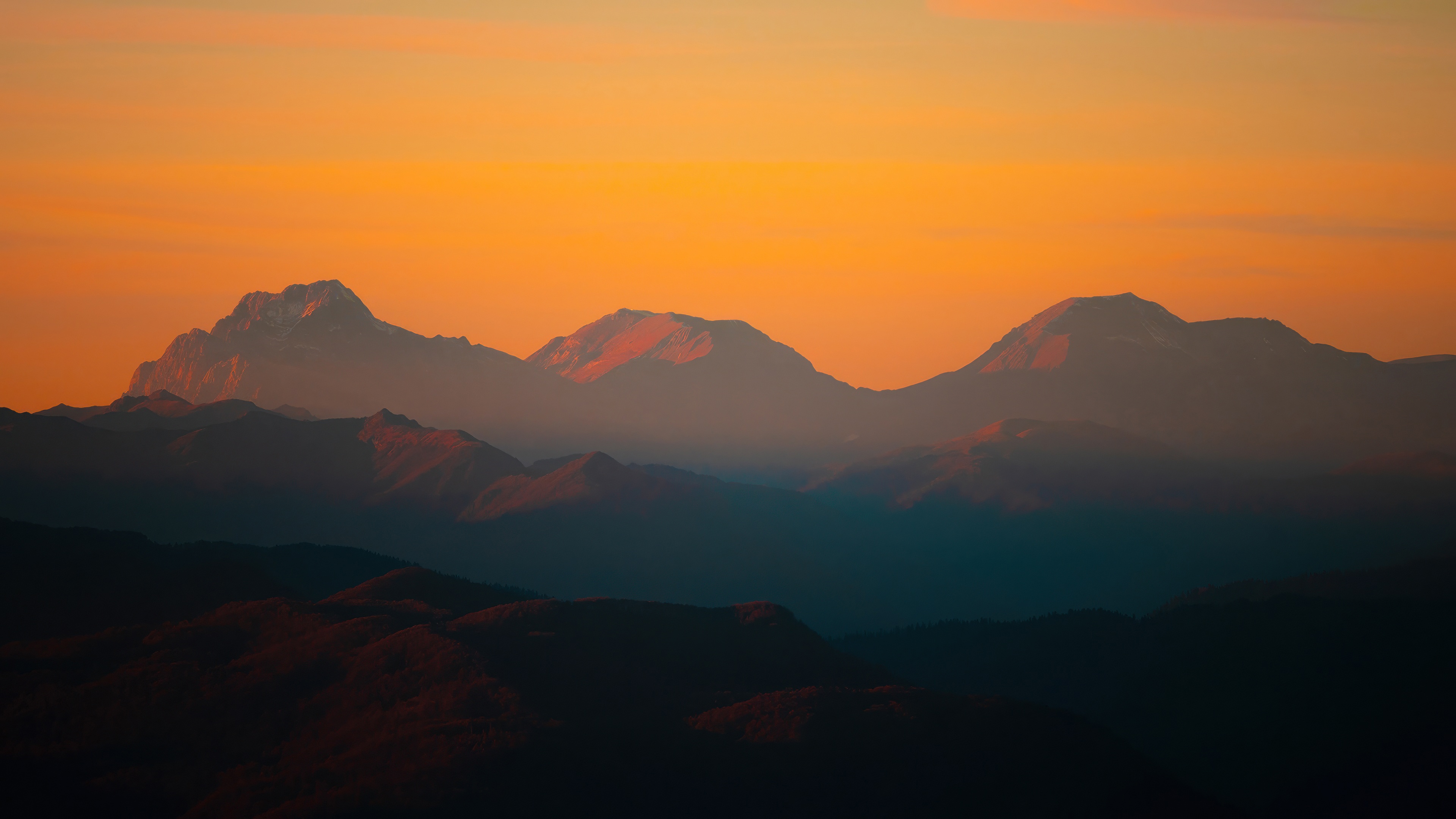Mountain peaks at sunrise with orange sky HD Wallpaper