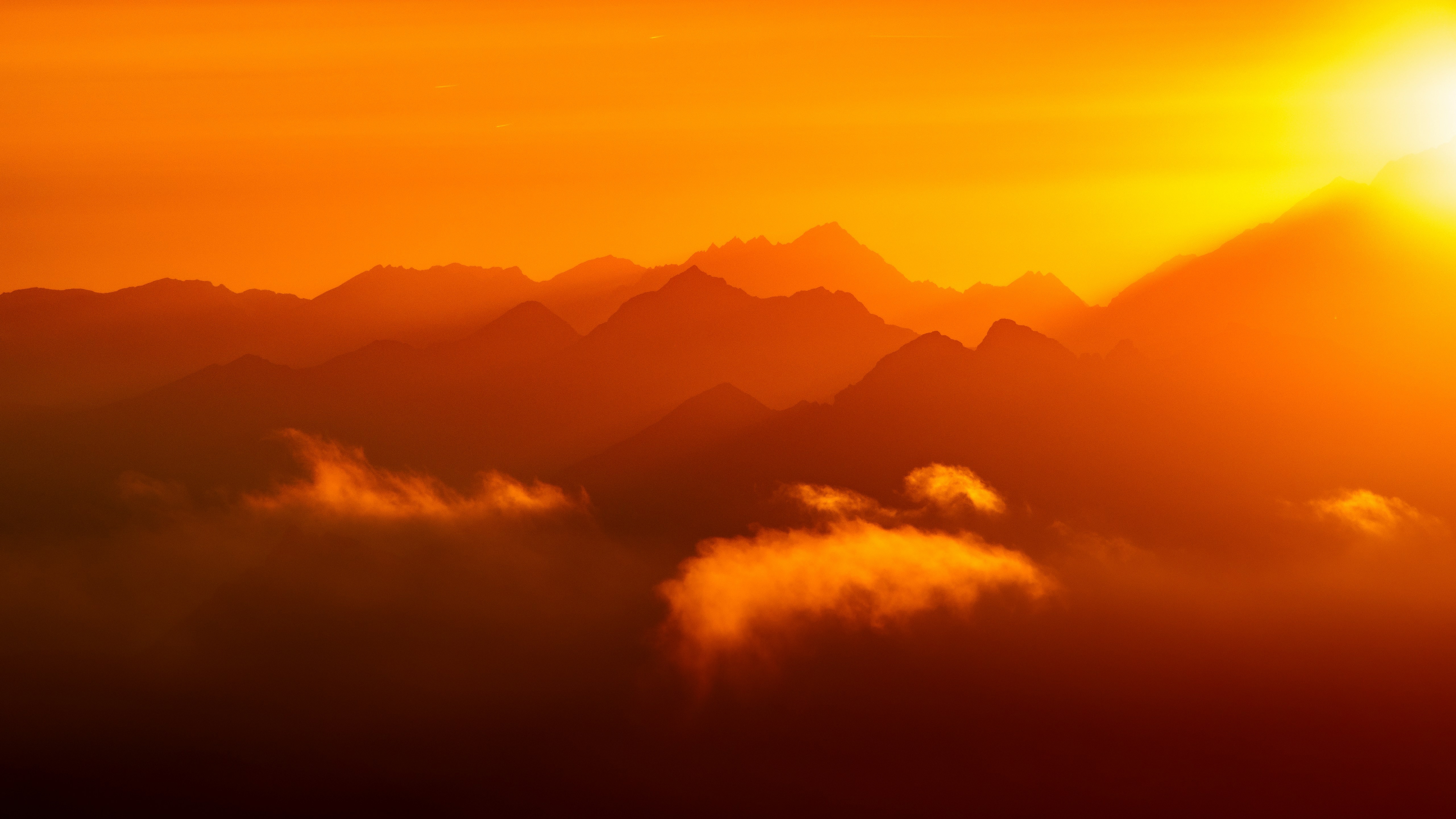 Sunset over a mountain range with clouds HD Wallpaper