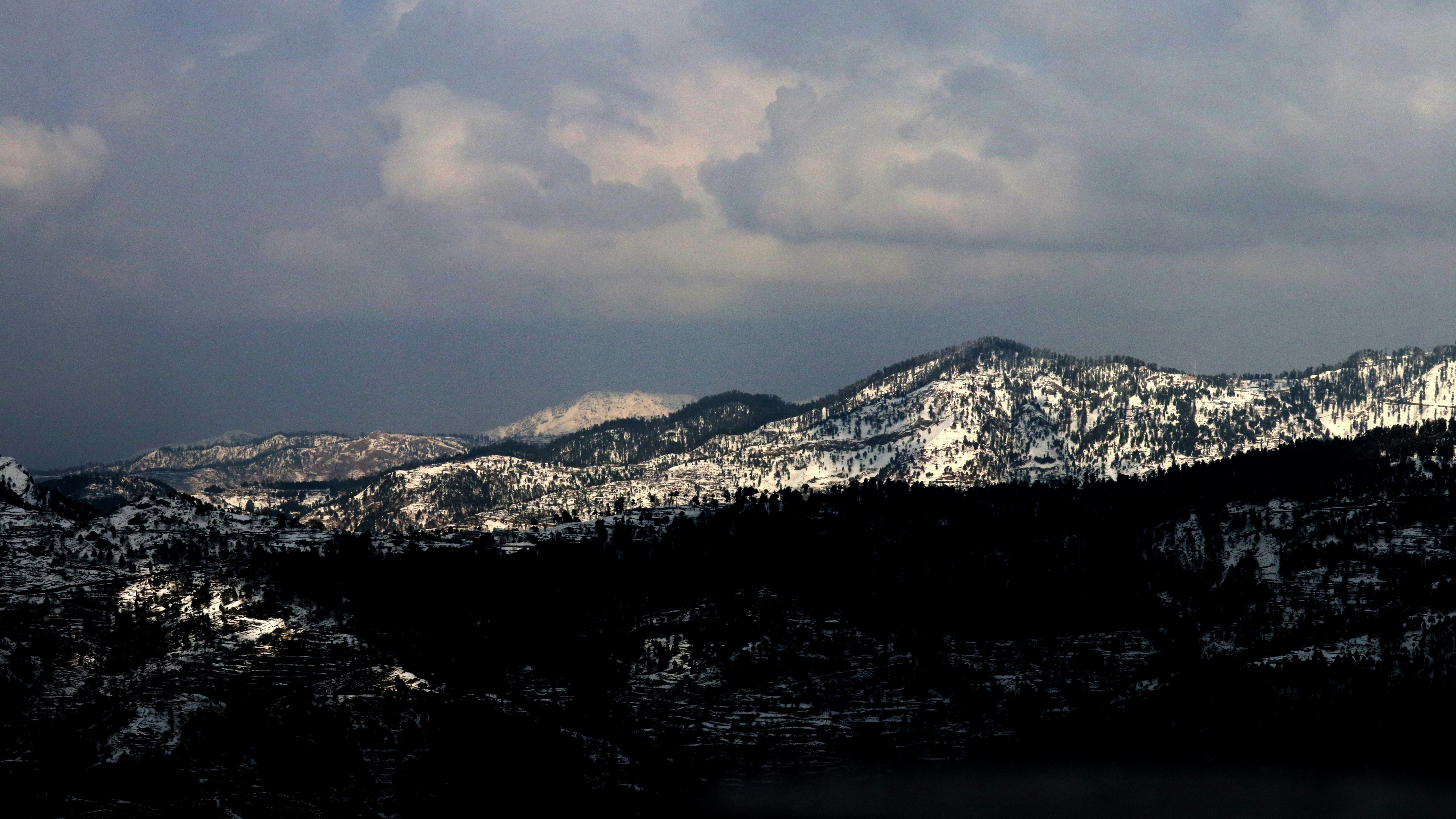 Snow-covered mountain range under cloudy sky HD Wallpaper