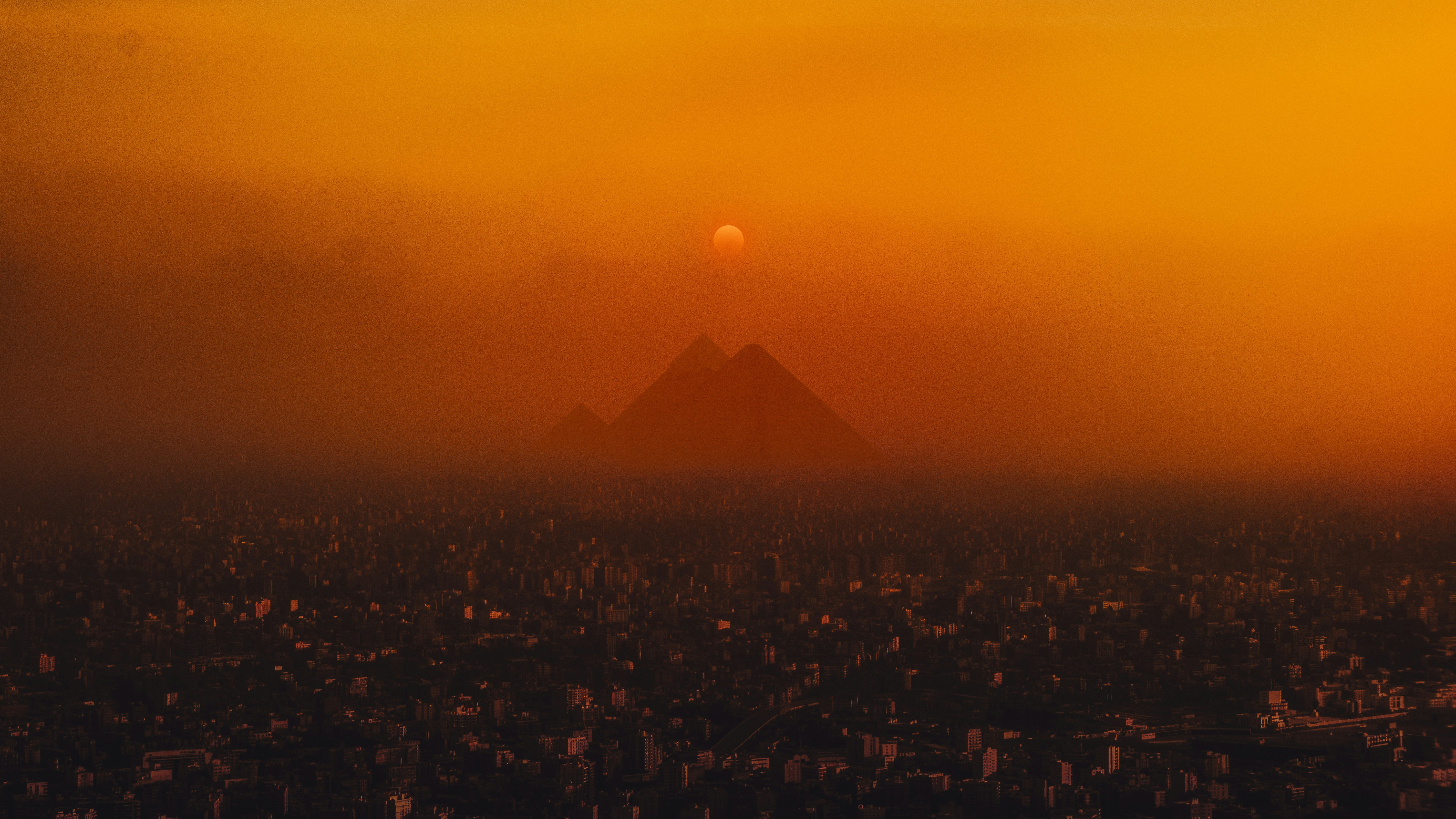 Sunset over the Pyramids of Egypt and a city HD Wallpaper
