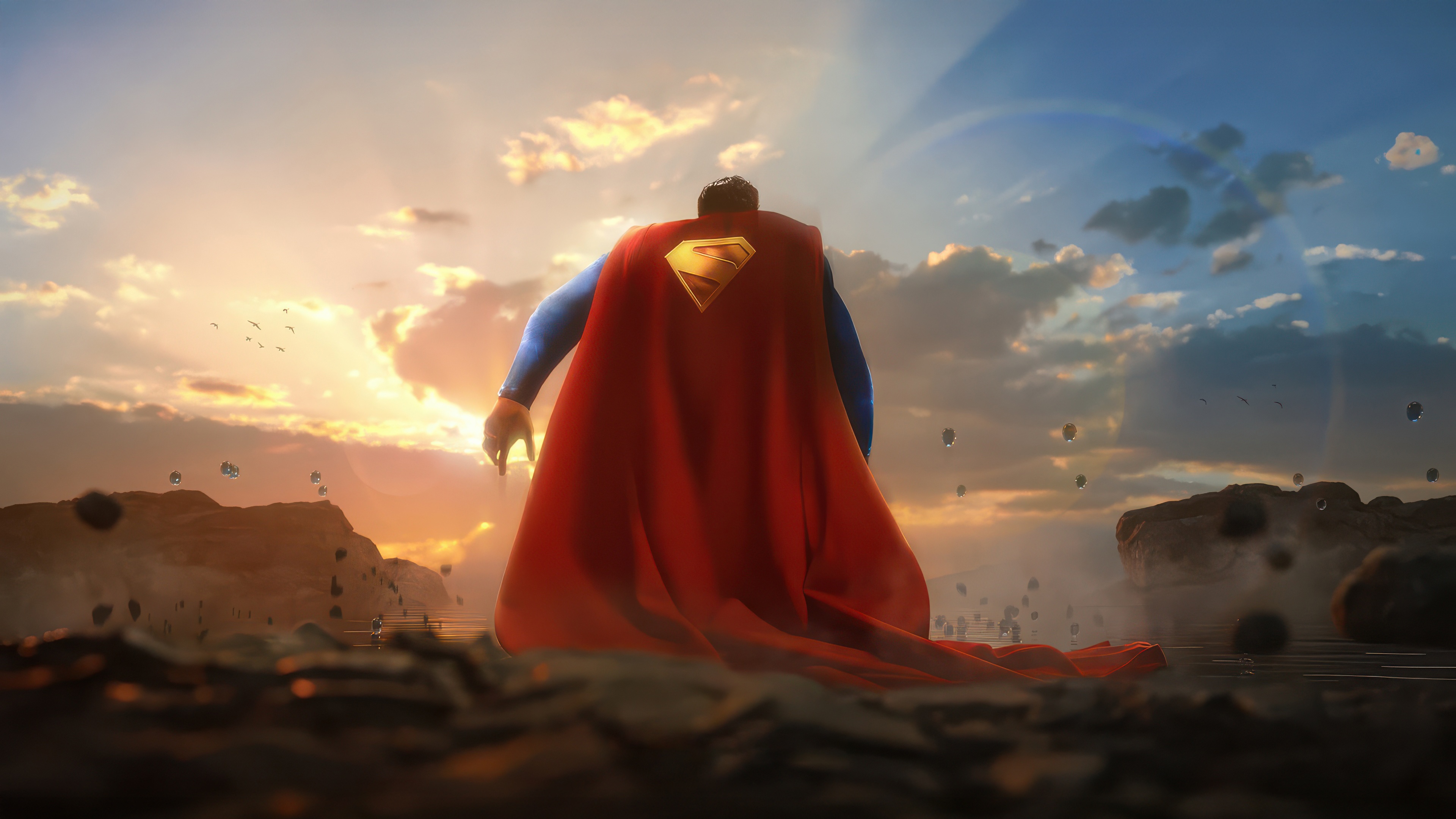 Superman stands on rocky terrain at sunset HD Wallpaper