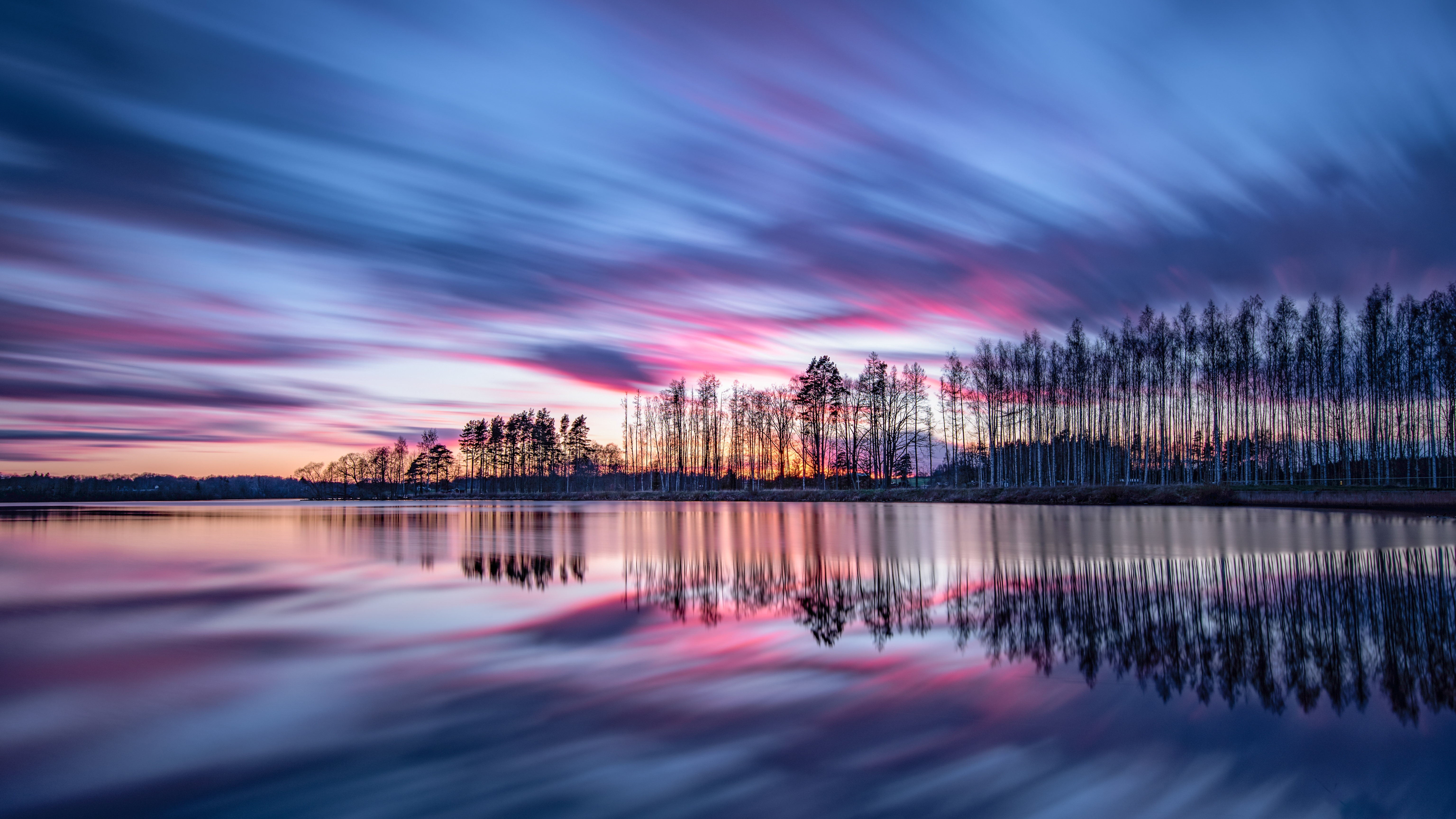Long exposure of trees reflecting on silent waters at sunset HD Wallpaper