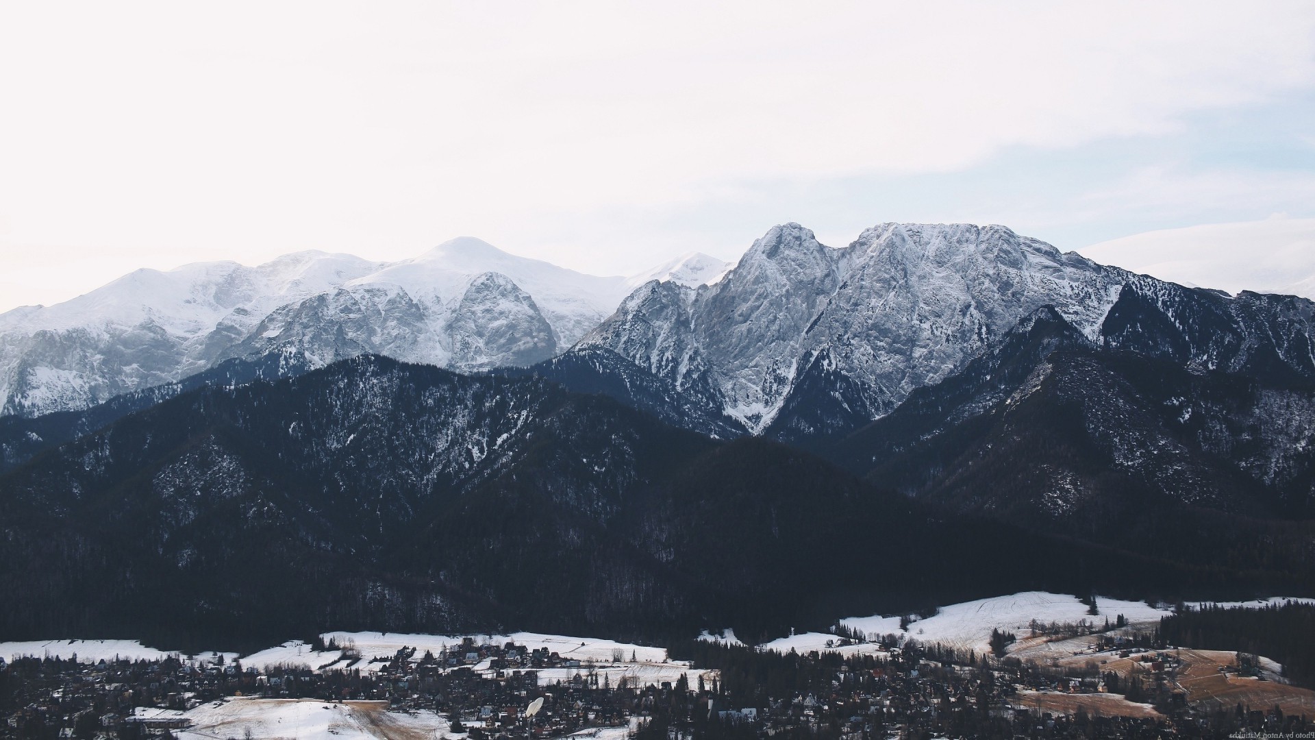 Snowy mountains overlooking a village in winter HD Wallpaper