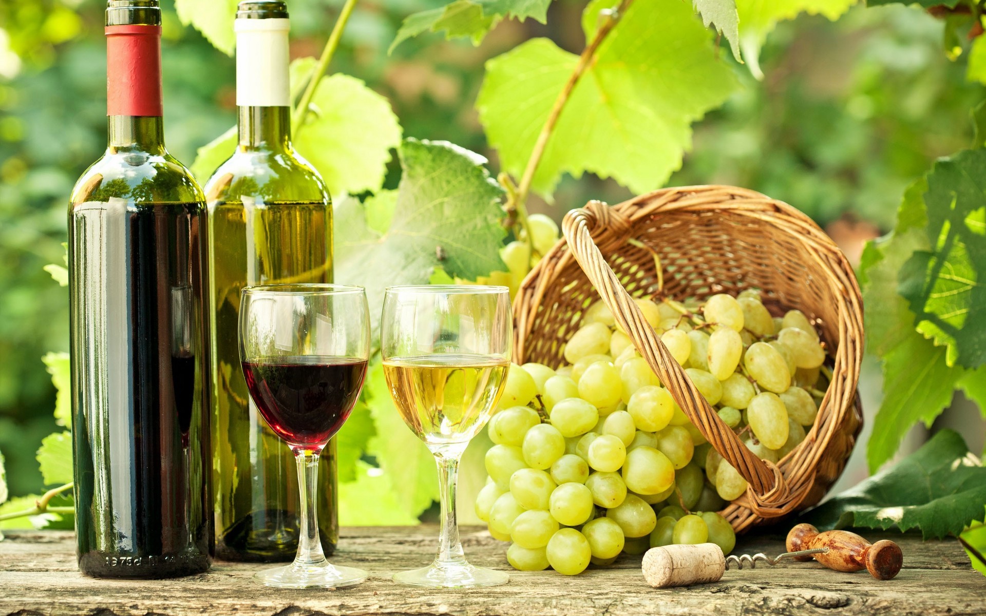 Wine bottles, glasses, grapes, and corkscrew on a table HD Wallpaper