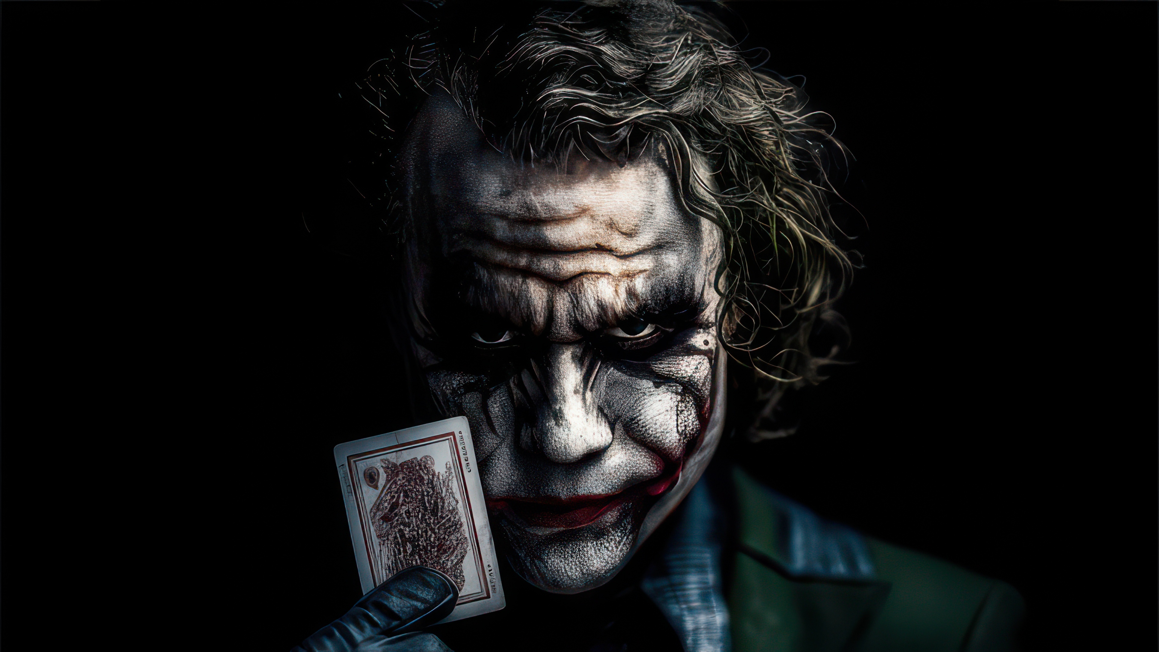 The Joker holding a playing card HD Wallpaper