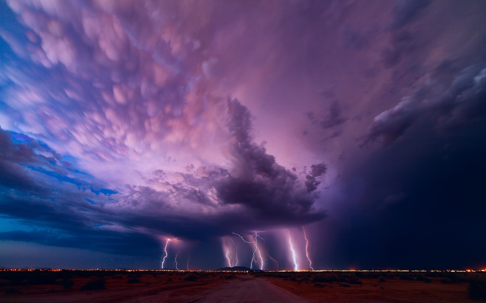Lightning strikes over a desert landscape at dusk HD Wallpaper