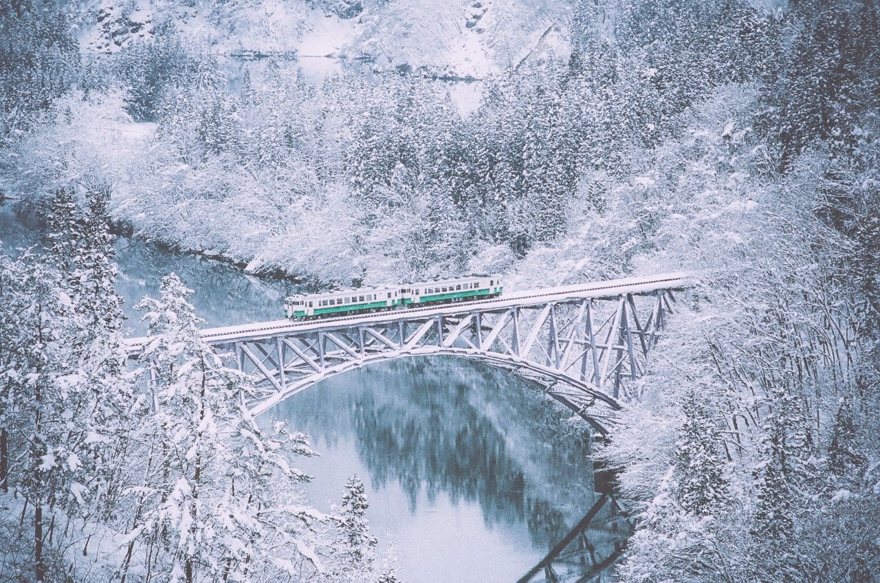 Train crossing a snowy bridge over a river HD Wallpaper
