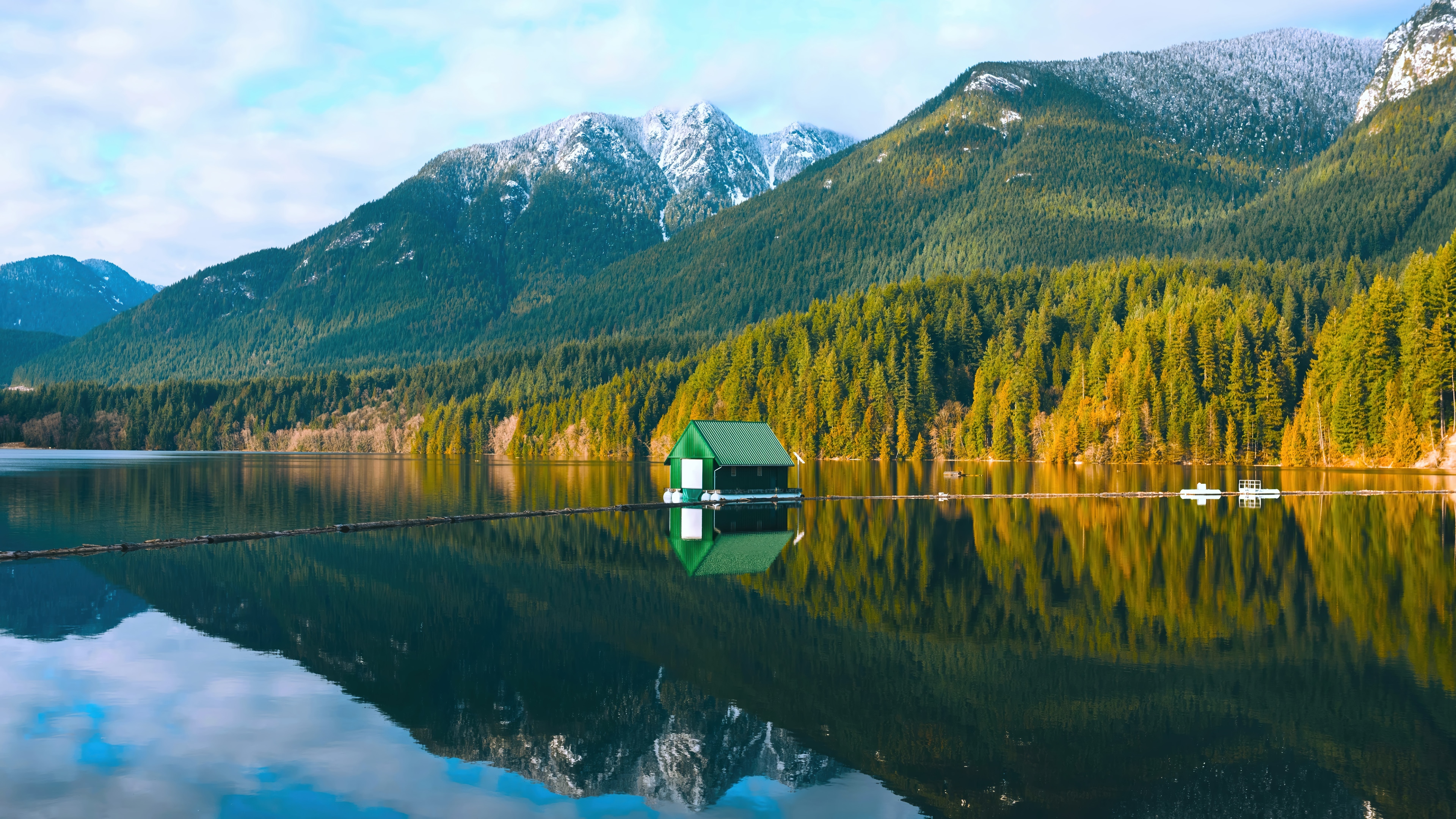 Green boathouse on a calm lake with snow-capped mountains HD Wallpaper