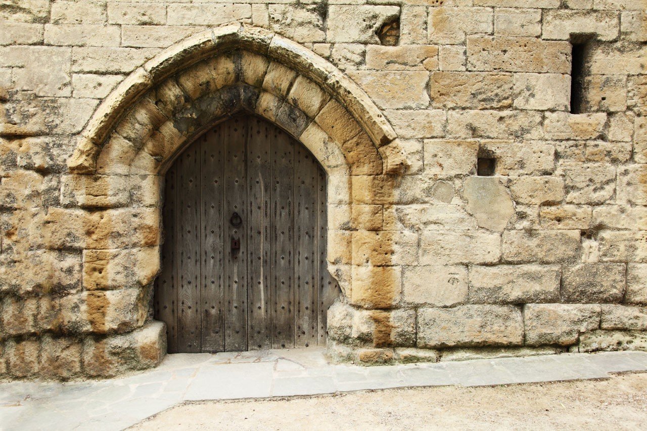 Ancient stone wall with a wooden arched doorway HD Wallpaper