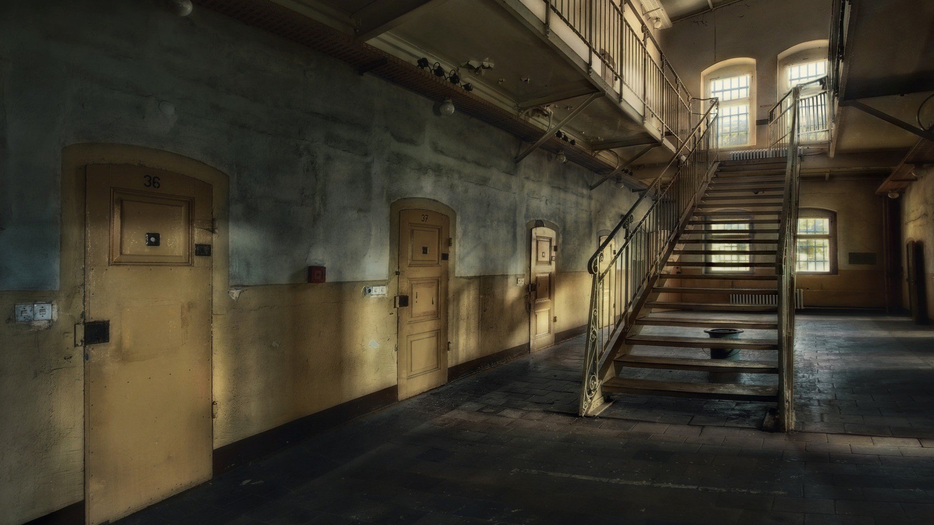 Abandoned prison hallway with stairs and cells HD Wallpaper