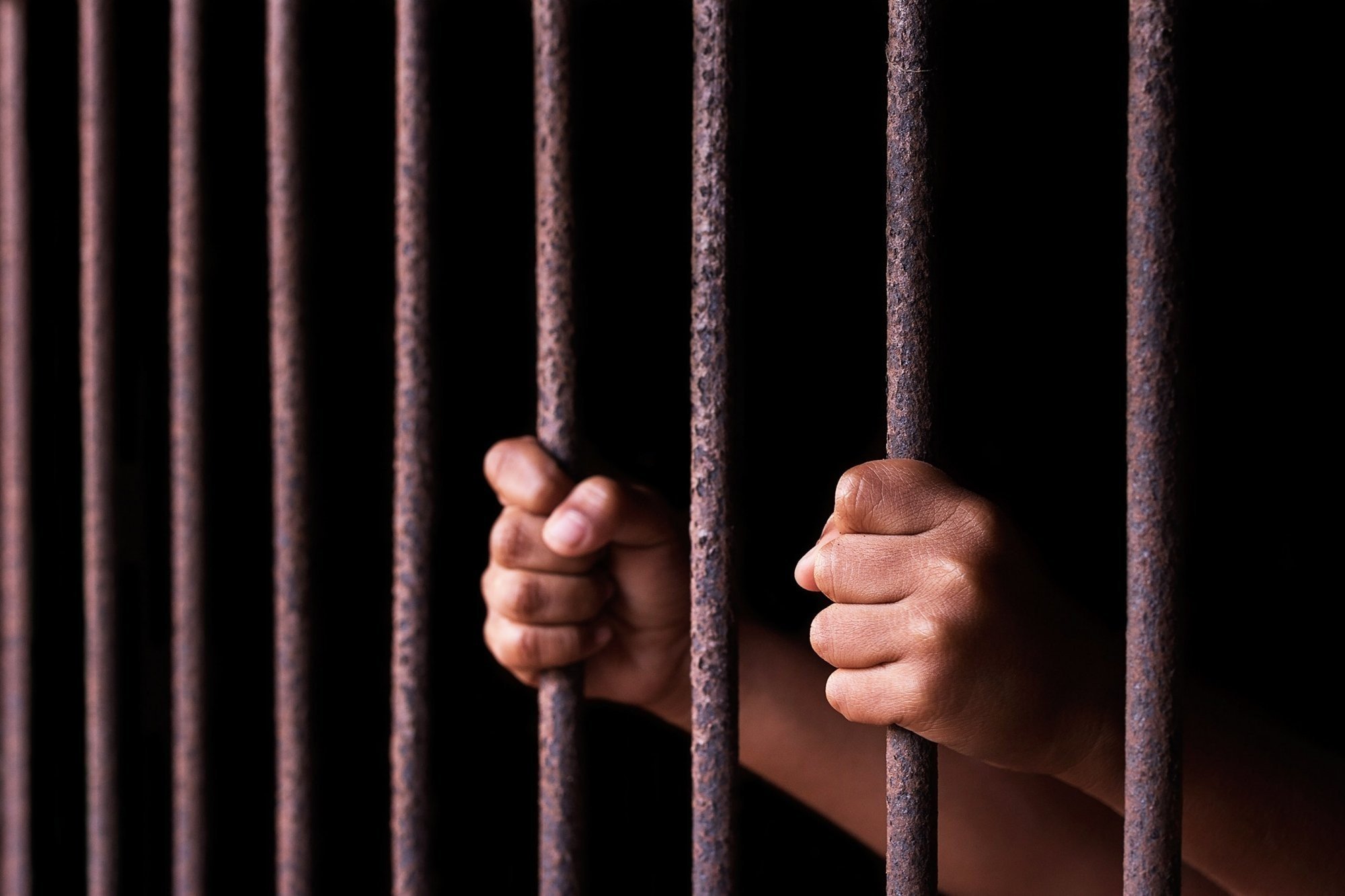Hands gripping prison bars HD Wallpaper