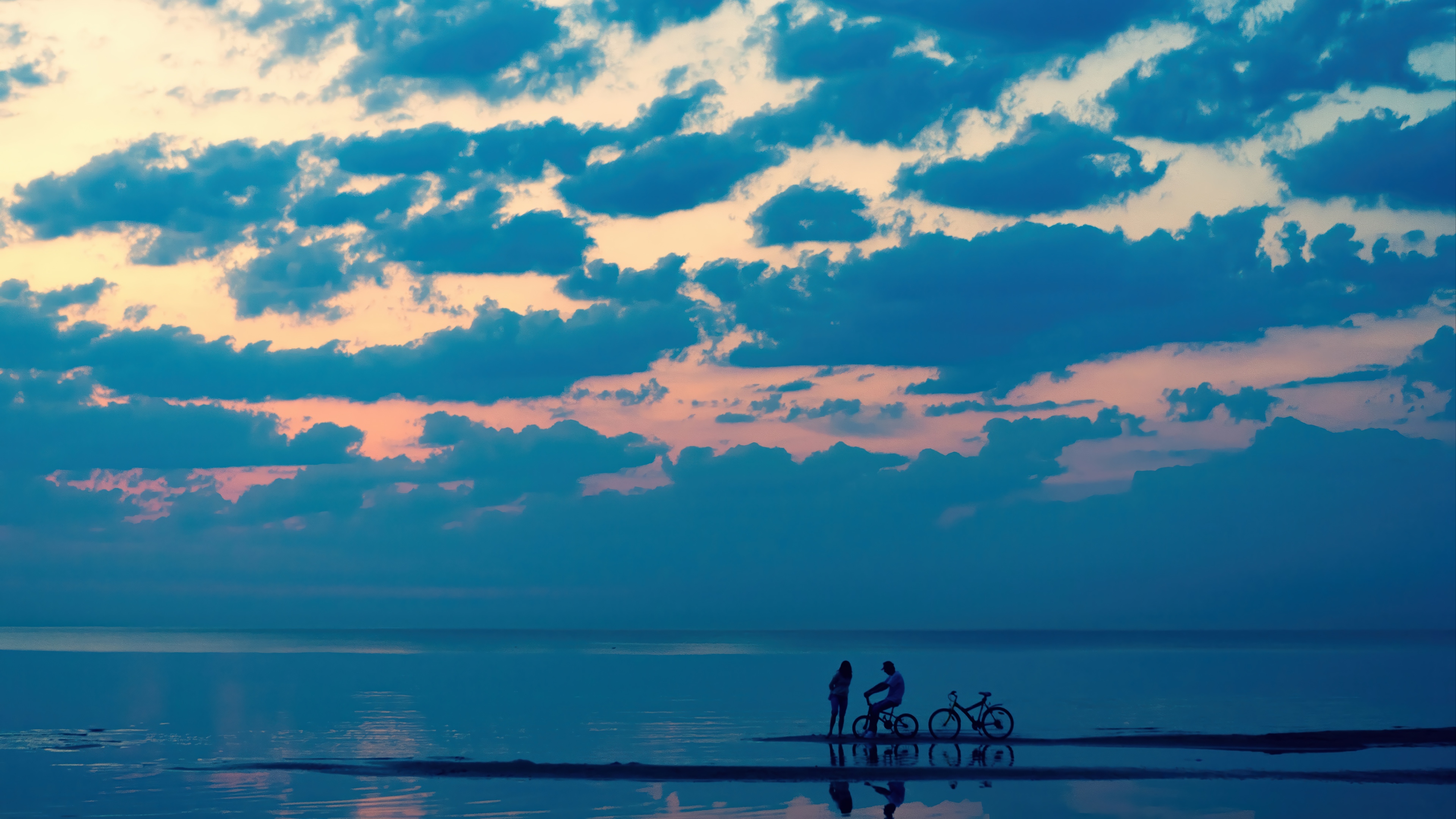 Couple with bicycles by the sea at sunrise 4K HD Wallpaper