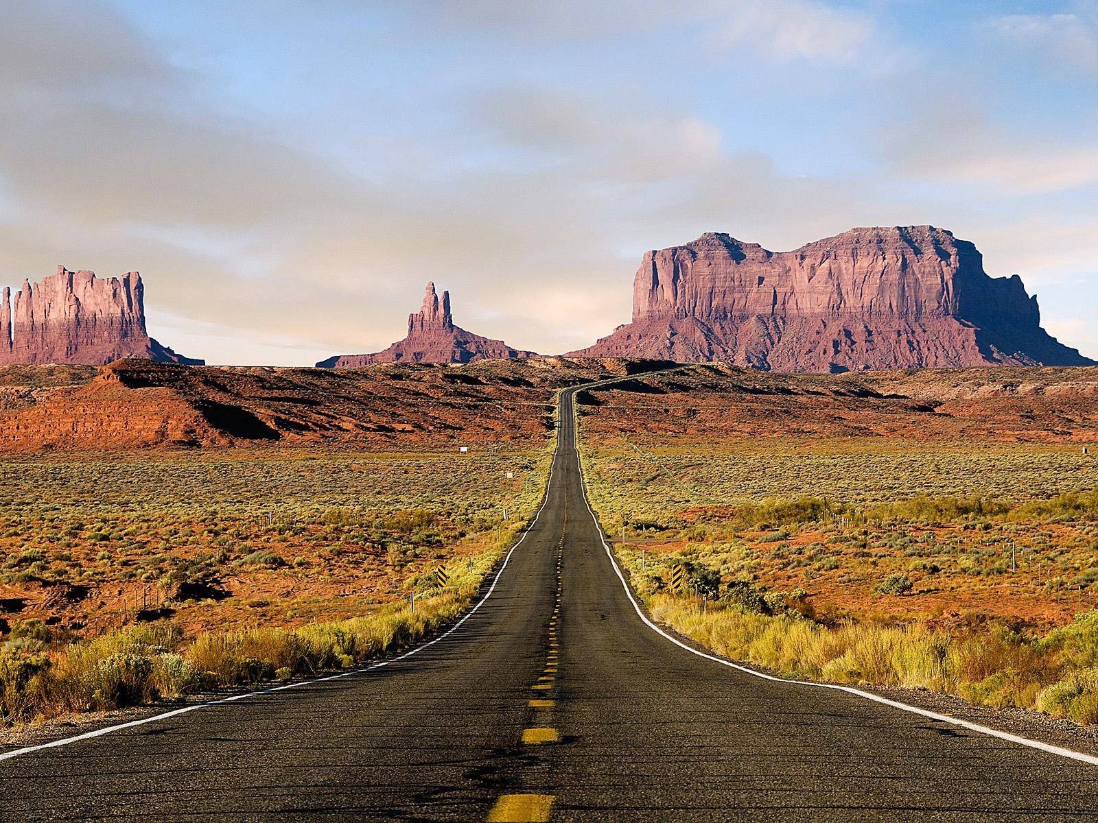 Monument Valley road with mesas under a cloudy sky HD Wallpaper