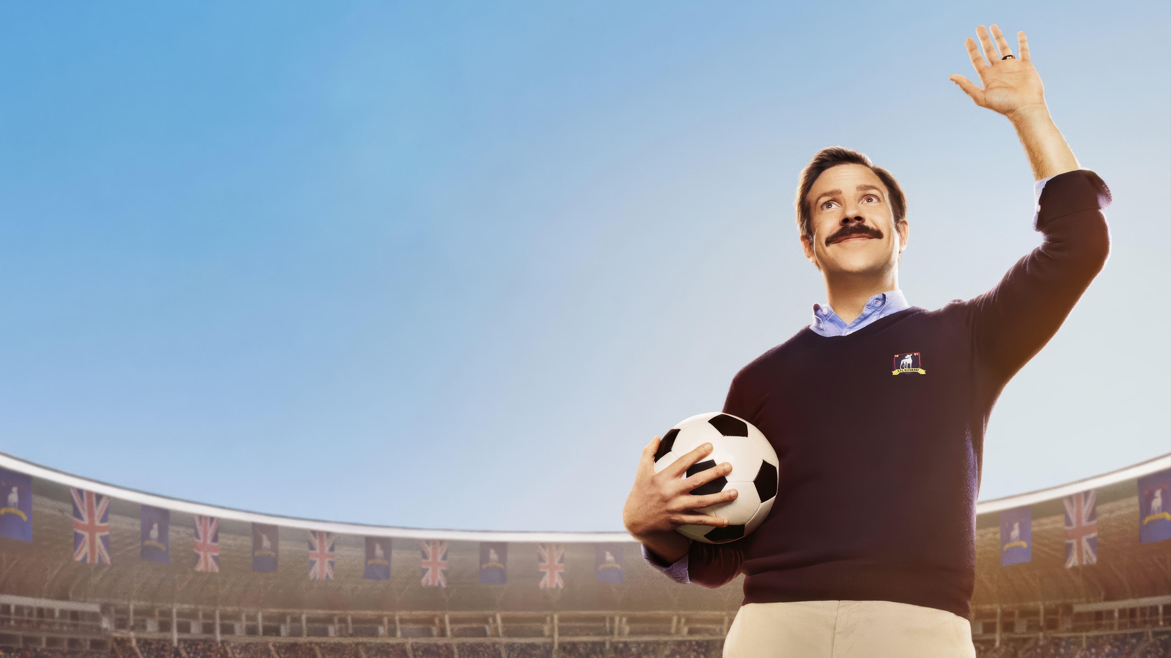 Ted Lasso holding a soccer ball in a stadium HD Wallpaper