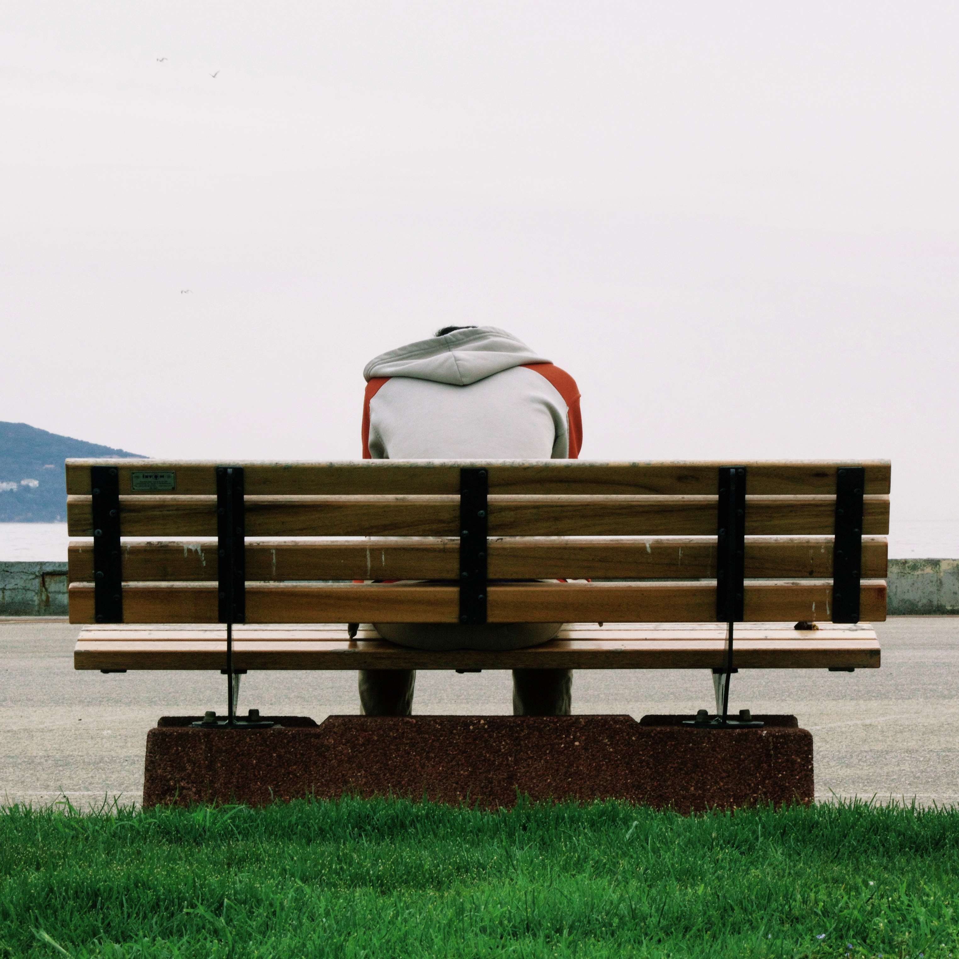Person sitting alone on a park bench HD Wallpaper