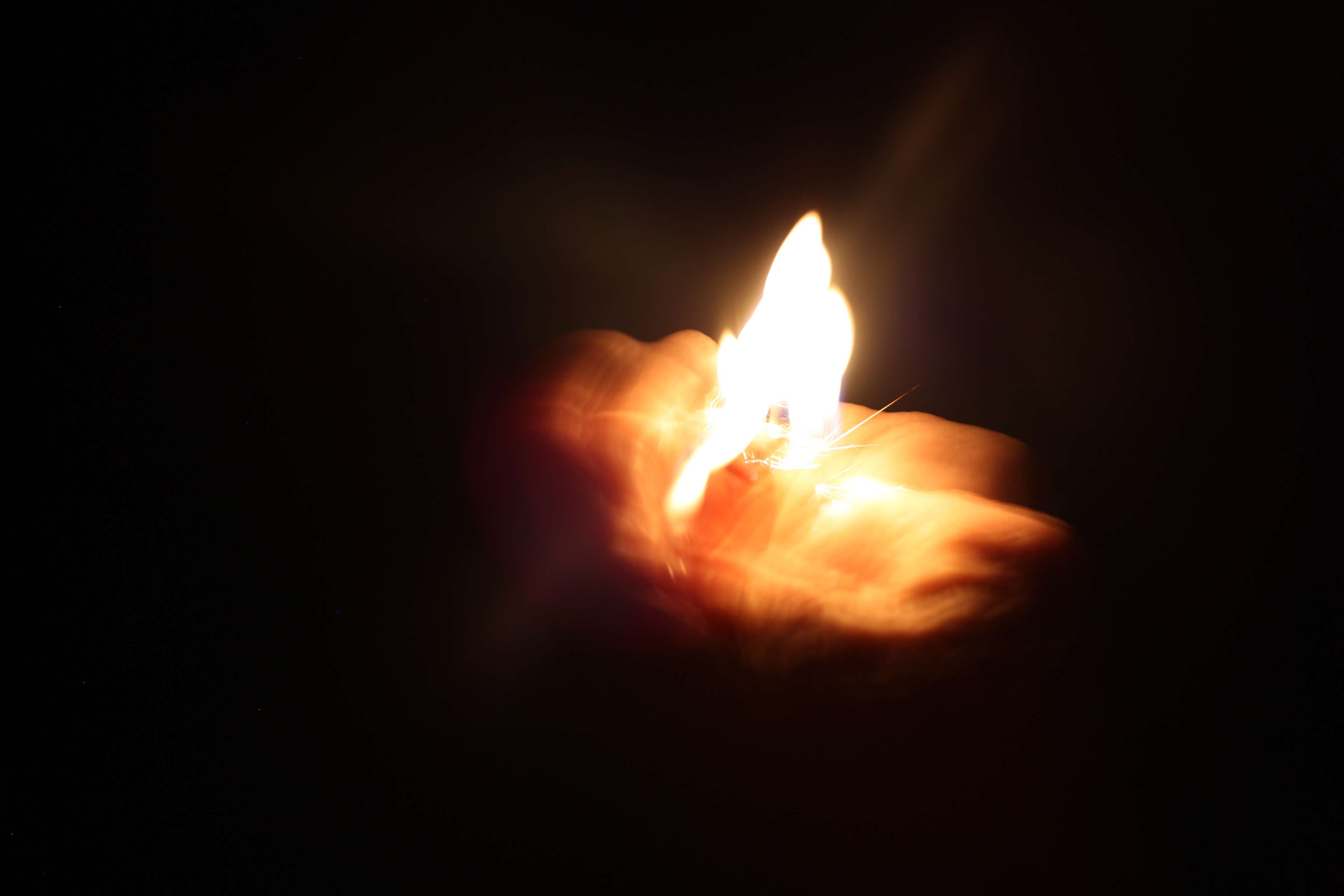 Hand holding a lighter with flames in darkness HD Wallpaper