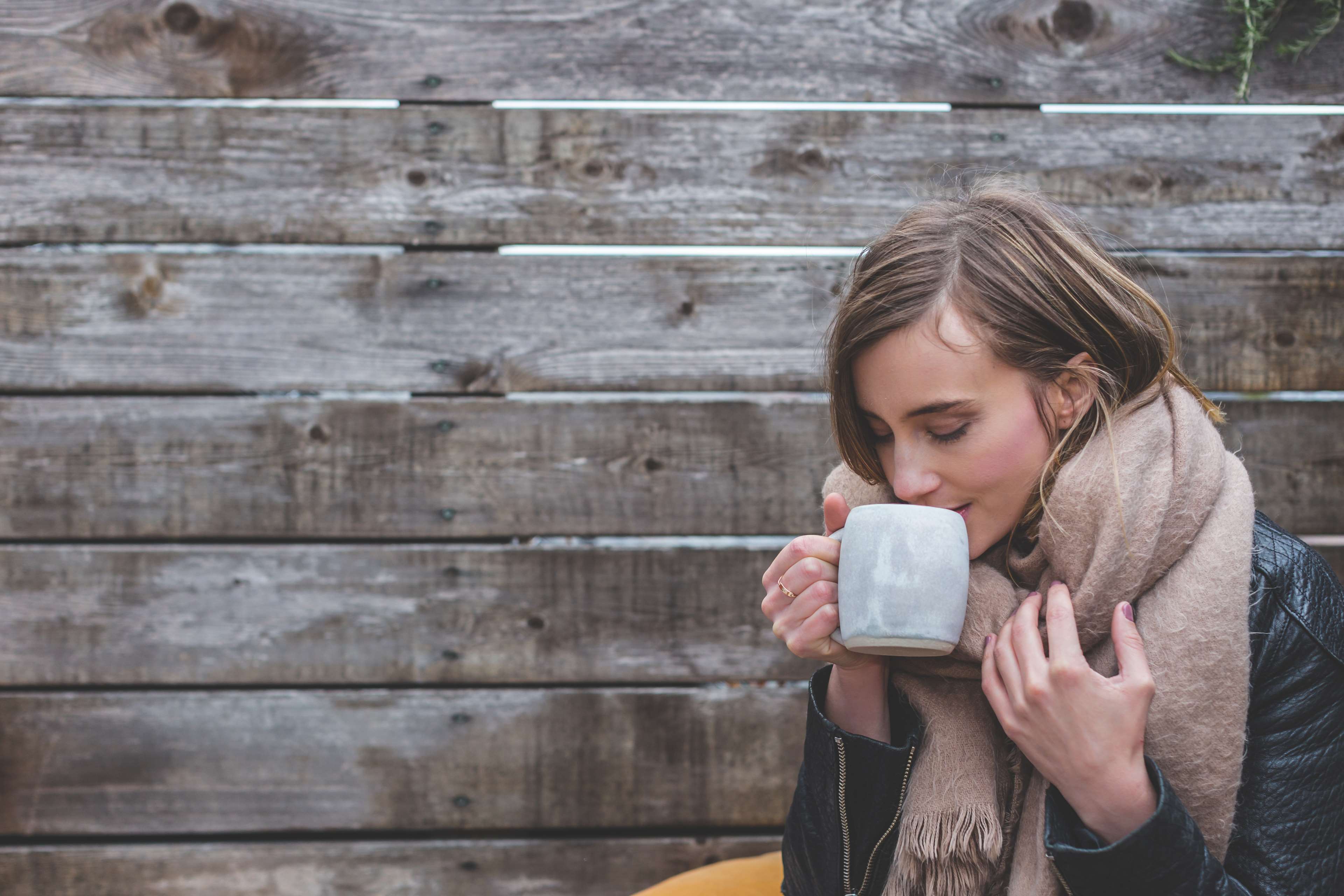 Woman drinking from a mug in front of a wooden wall 4K HD Wallpaper