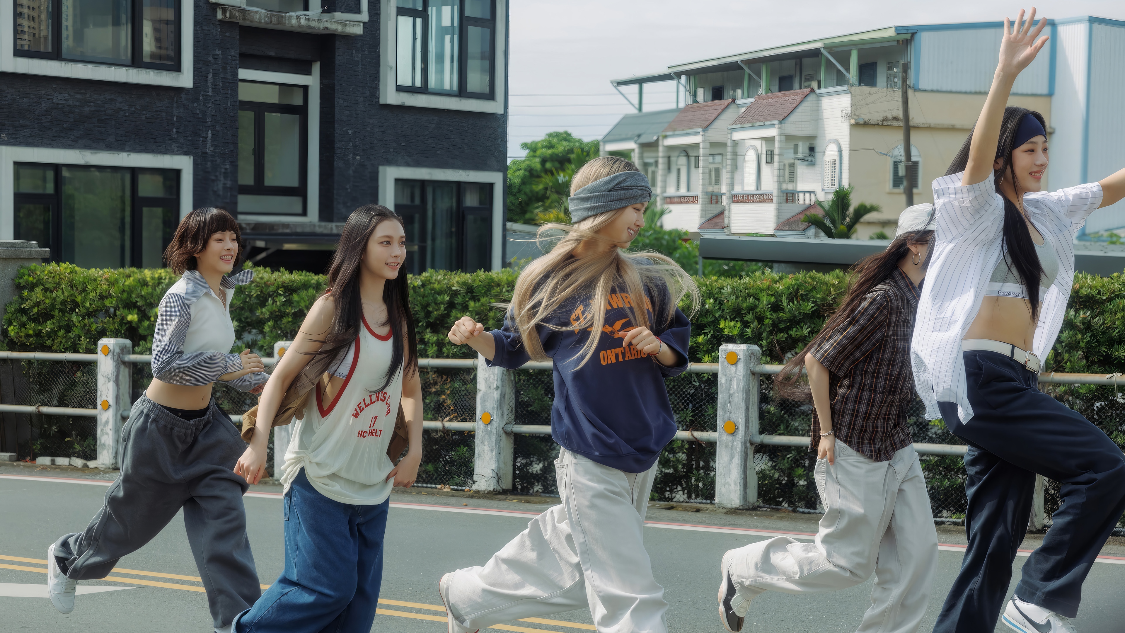 NewJeans members running on a street HD Wallpaper