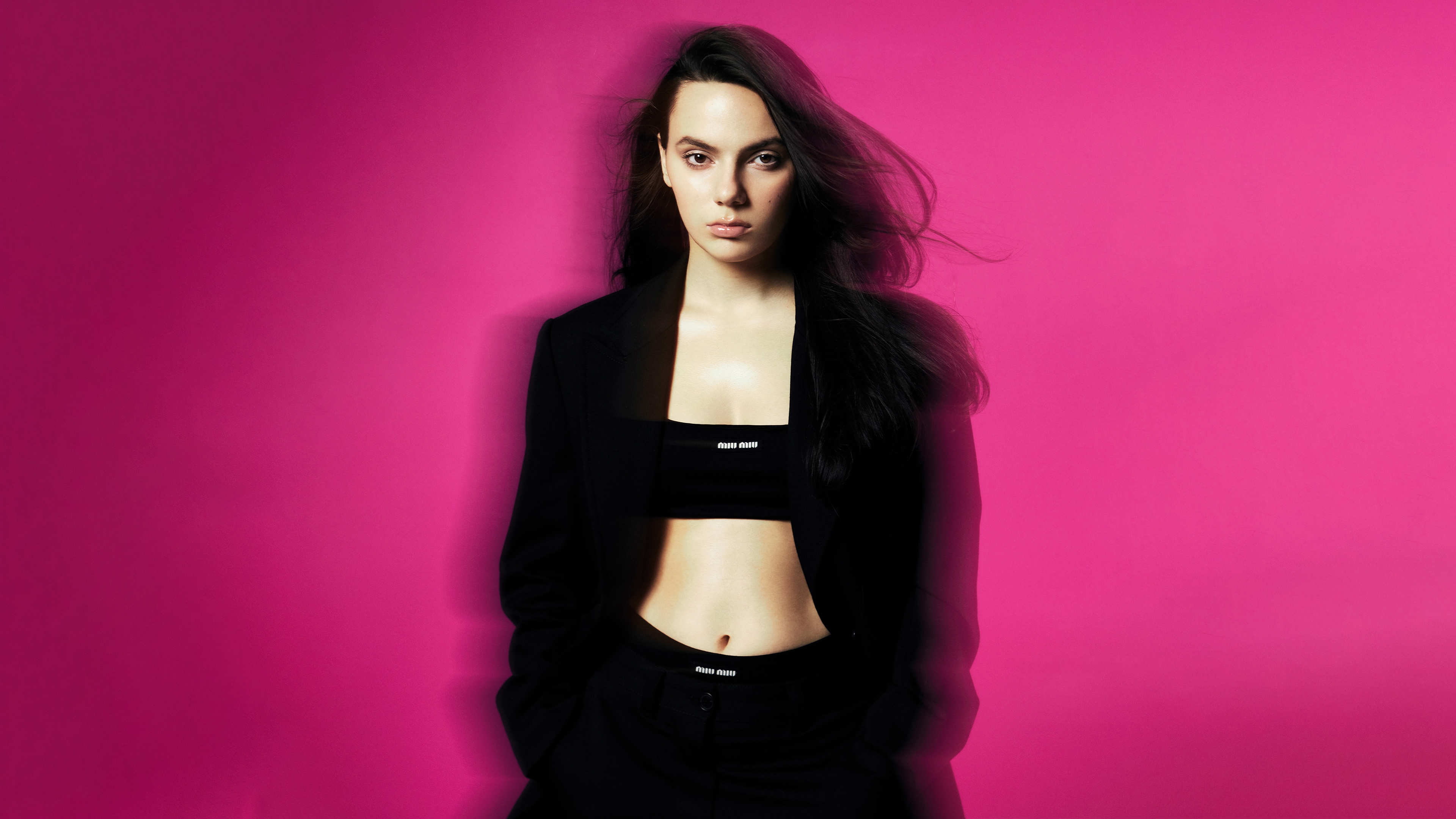 Dafne Keen in black outfit on pink background 4K HD Wallpaper